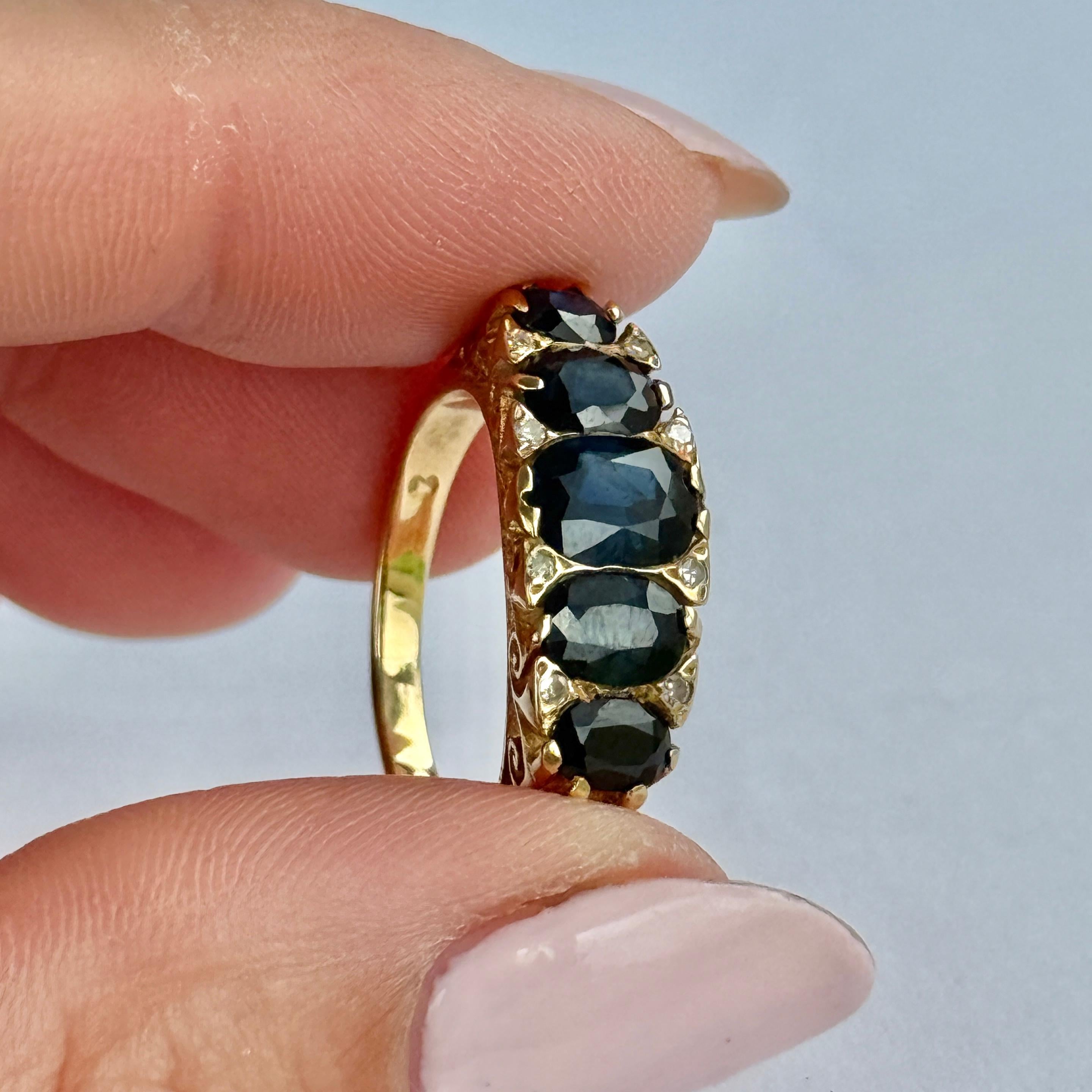 This gorgeous ring holds five deep blue sapphires. The central sapphire measures 30pts, the next largest are 20pts each and the smaller sapphires measure 15pts. There are also pairs of diamond points in between each dark blue stone. Modelled in 18