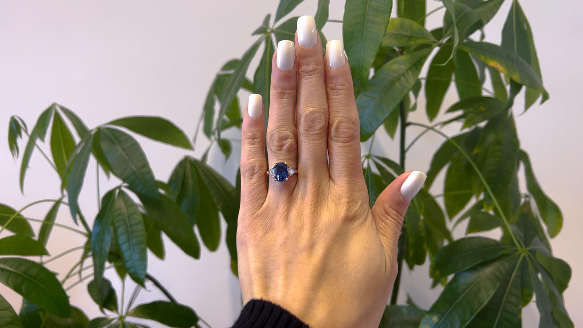 Un Anillo Vintage de Tres Piedras de Zafiro y Diamantes de Oro Amarillo de 18k. Con un zafiro talla cojín de 4,69 quilates. Acentuado por dos diamantes talla trillón con un peso total aproximado de 0,80 quilates, de color G-H y claridad SI.