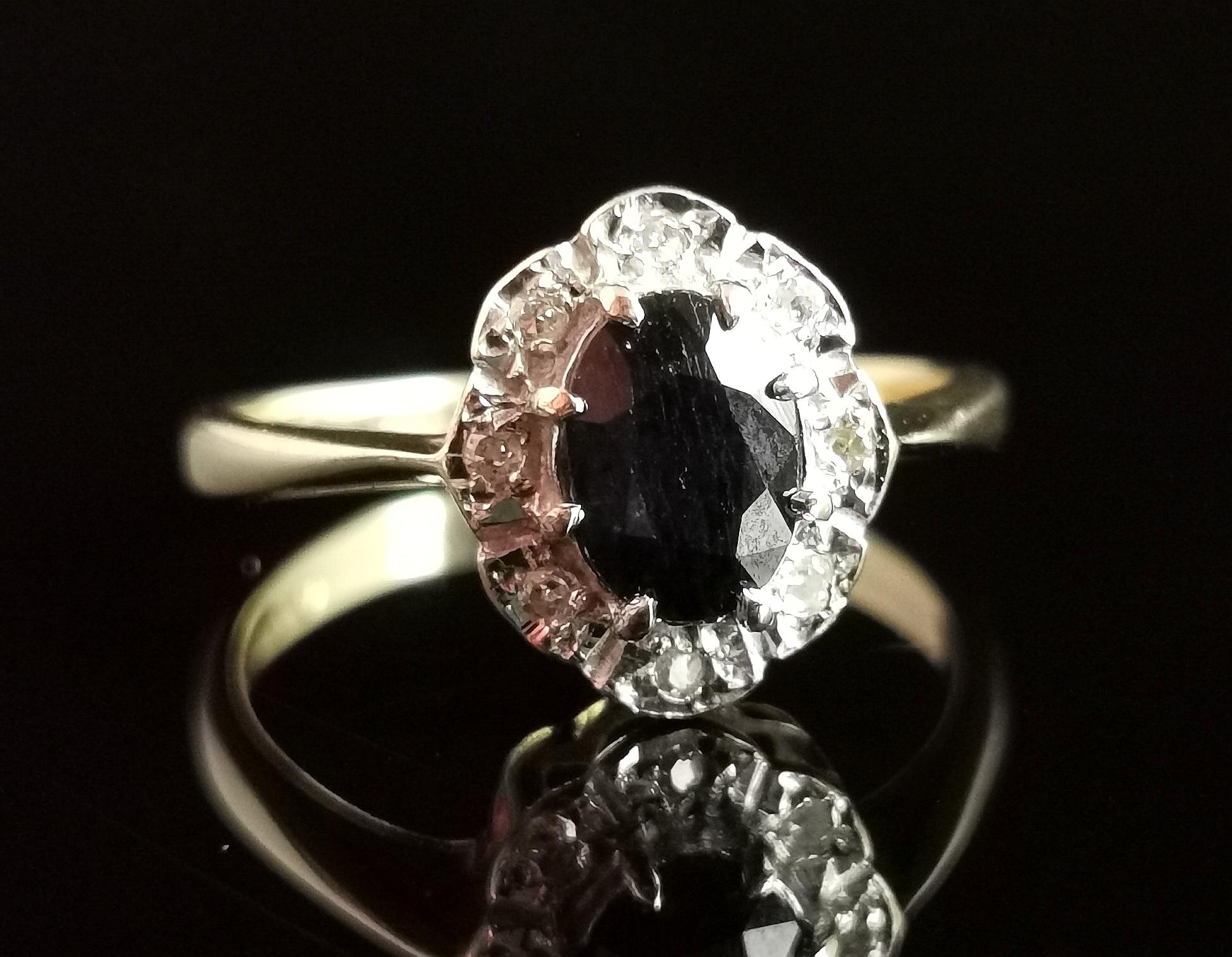 A beautiful vintage 1970s Sapphire and diamond cluster ring.

A decadent beauty, it has been made to stand out and the dark blue, oval cut sapphire takes centre stage.

The sapphire is surrounded by a halo of crisp white diamond chips giving a