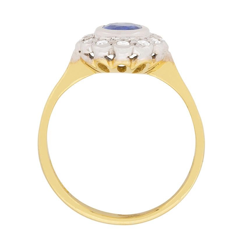 This delicate cluster ring features a sapphire in the centre weighing 0.50 carat. It is a lovely pale blue and has been haloed by sparkling diamonds. The diamonds are 8-cuts and have a combined weight of 0.24 carat. They are also rub over set and