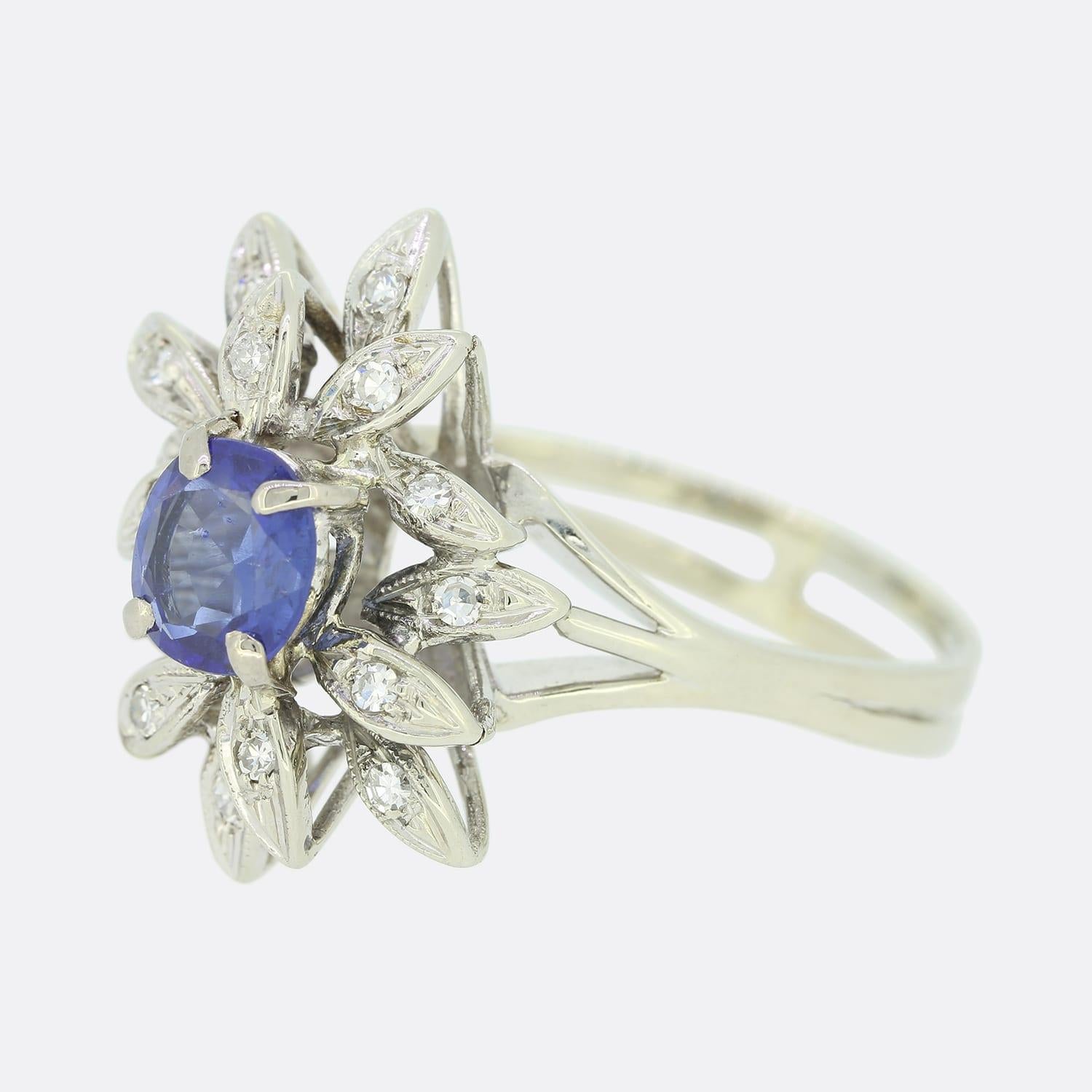 Questo è un bellissimo anello vintage con zaffiri e diamanti. L'anello presenta uno zaffiro centrale con taglio a cuscino circondato da diversi diamanti a taglio singolo in un'incastonatura astratta. Lo zaffiro è di colore blu reale ed è montato su