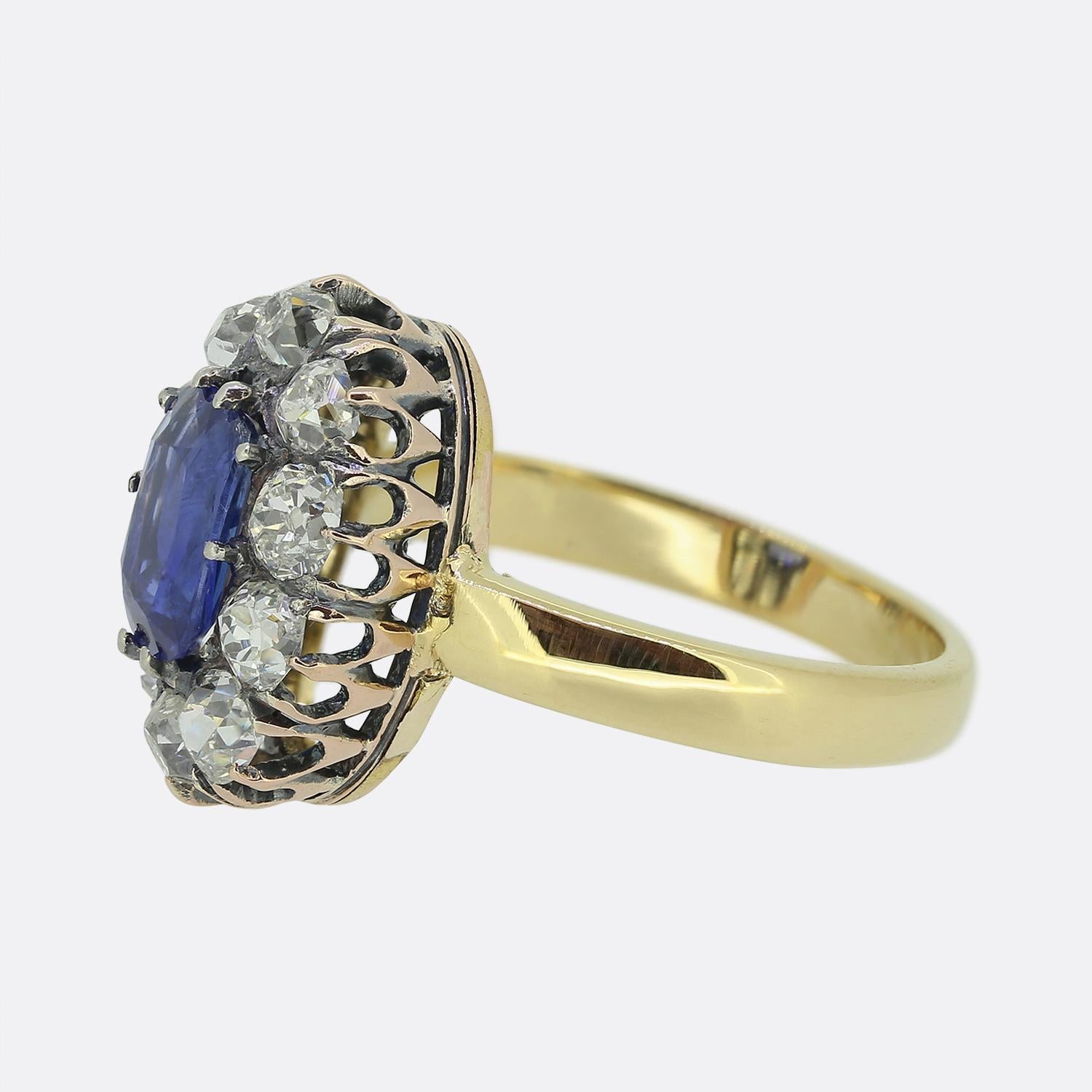 Here we have a stunning sapphire and diamond cluster ring. This antique piece features an single oval shaped cushion cut natural unheated sapphire at the centre of the face possessing a bright cornflower blue colour tone. This principle stone is