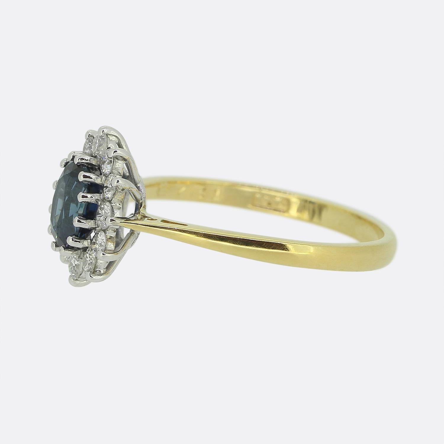 Ecco un delizioso anello a grappolo dallo stile classico. Questo pezzo vintage è stato realizzato in caldo oro giallo 18 carati e presenta uno zaffiro ovale sfaccettato al centro del quadrante. Questa pietra principale è leggermente rialzata in una
