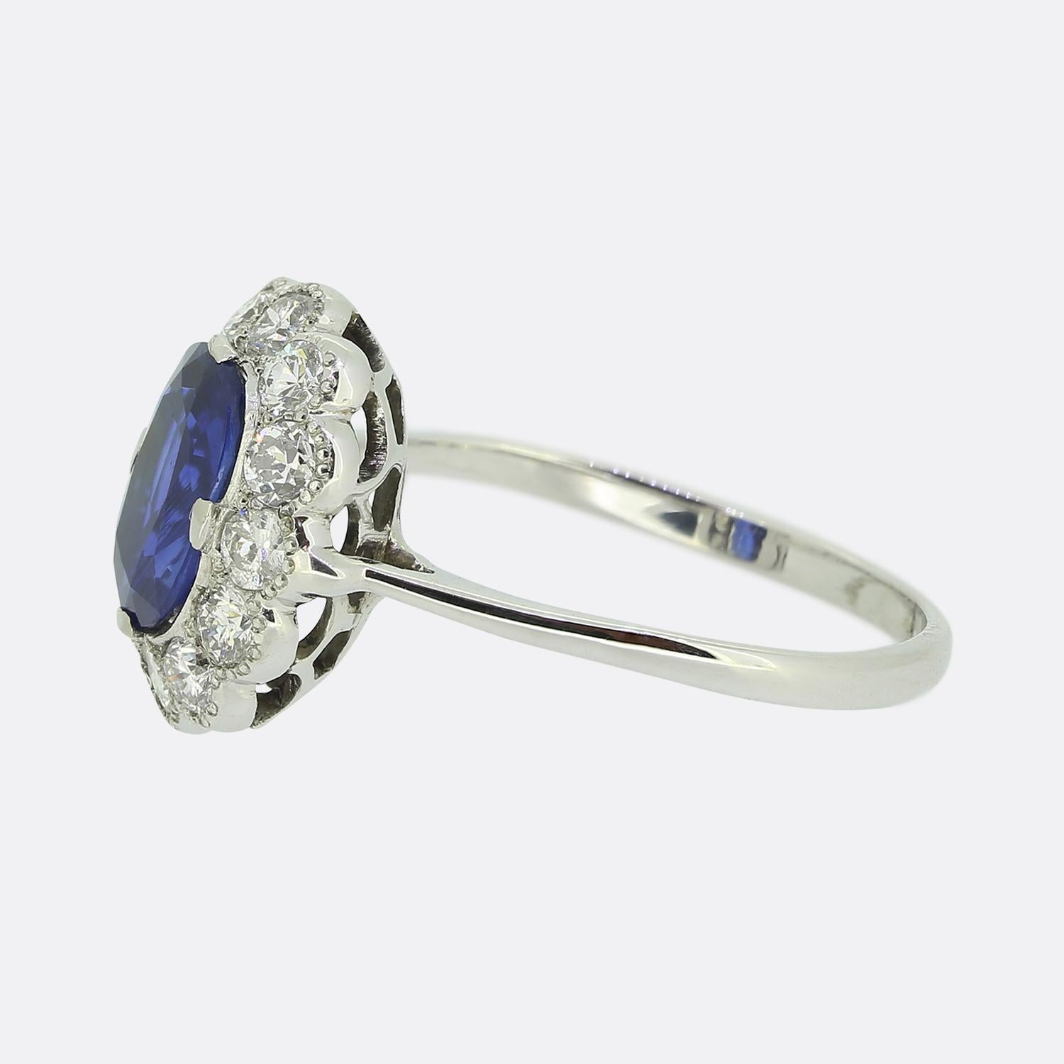 This is a wonderful sapphire and diamond cluster ring crafted in 18ct white gold. The central sapphire is a beautiful rich blue, unheated and an oval cut. Surrounding the sapphire there are twelve bright white diamonds that sit in rubover mounts
