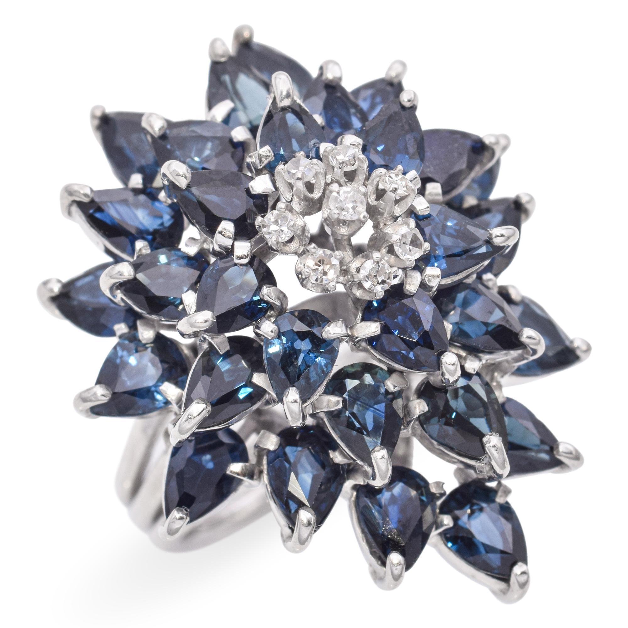 A striking ring featuring a floral design with deep blue pear-shaped sapphires and round brilliant diamonds set in white precious metal alloy.

Weight: 10.7 grams 
Stone: 3.6tcw Sapphire, 0.12tcw Diamond 
Measurements: 24.8 x 29.2 x 16mm 
Ring
