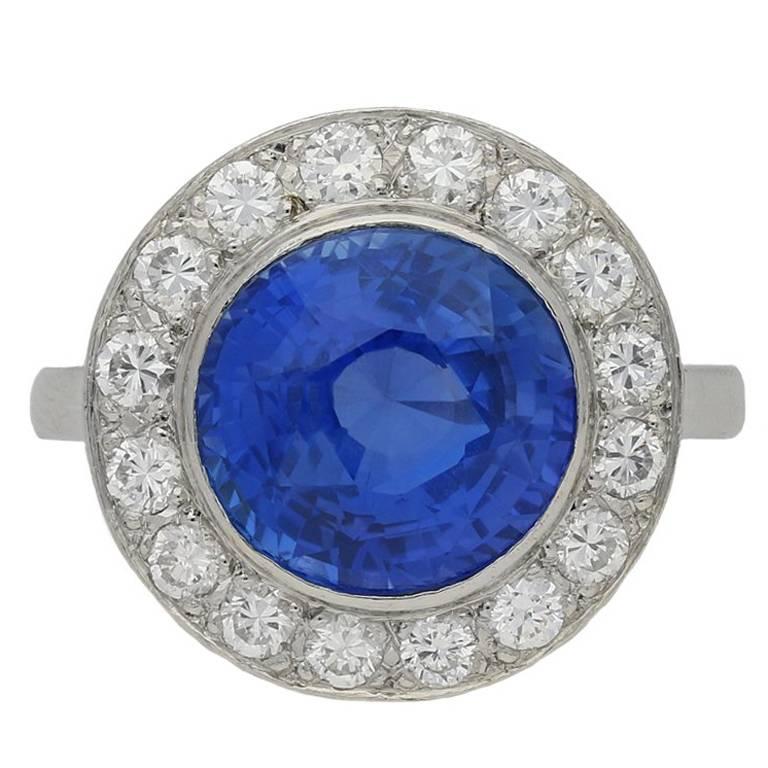 Vintage sapphire and diamond coronet cluster ring. Centrally set with a round double brilliant natural unenhanced Ceylon sapphire in an open back rubover setting with an approximate weight of 5.20 carats, surrounded by sixteen round brilliant cut