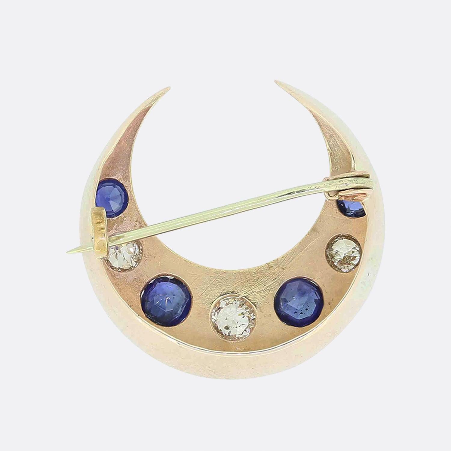 This is a gorgeous sapphire and diamond set crescent moon brooch. It is crafted in 9ct yellow gold, featuring a single row of claw set old cut diamonds and natural blue sapphires. The brooch also features a secure pin and c clasp for added security