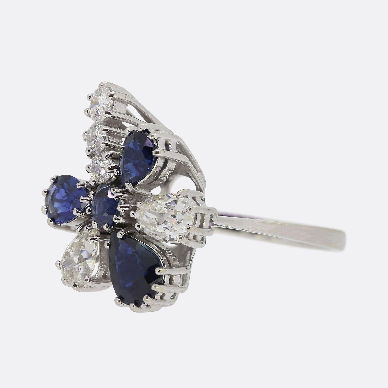 Aquí tenemos un maravilloso anillo vintage en racimo de zafiros y diamantes. El anillo presenta cuatro zafiros talla pera, dos diamantes talla pera vieja y tres diamantes talla brillante redondos. El anillo es de oro blanco de 18 quilates y las