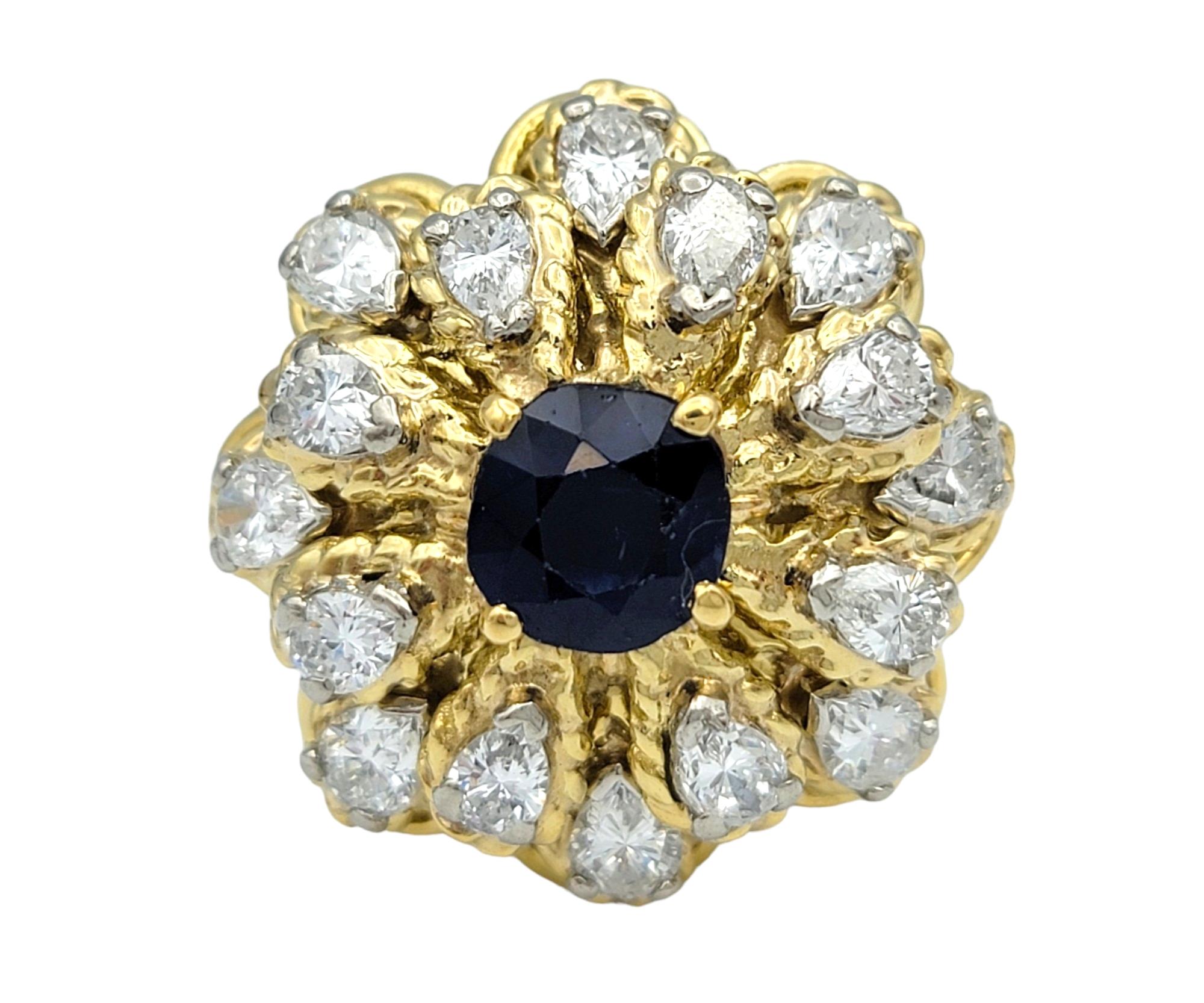 Ring Size: 3.75

This gorgeous blue sapphire and diamond flower design cocktail ring set in 18 karat yellow gold is a mesmerizing piece that exudes elegance and charm. At its center, a vibrant blue sapphire dazzles with its rich color and