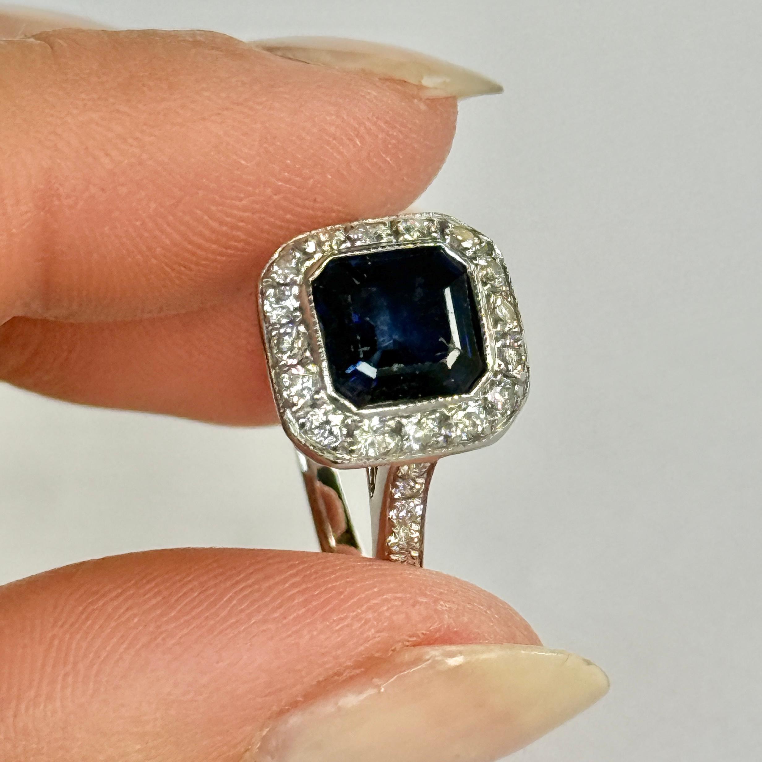 This ring is gorgeous and holds an inky but sapphire at the centre of a halo of sparkling diamonds. The sapphire measures 75pts and the diamond total is approx 60pts.  Modelled in platinum and stones also set in platinum. 

Ring Size: N or 6 3/4