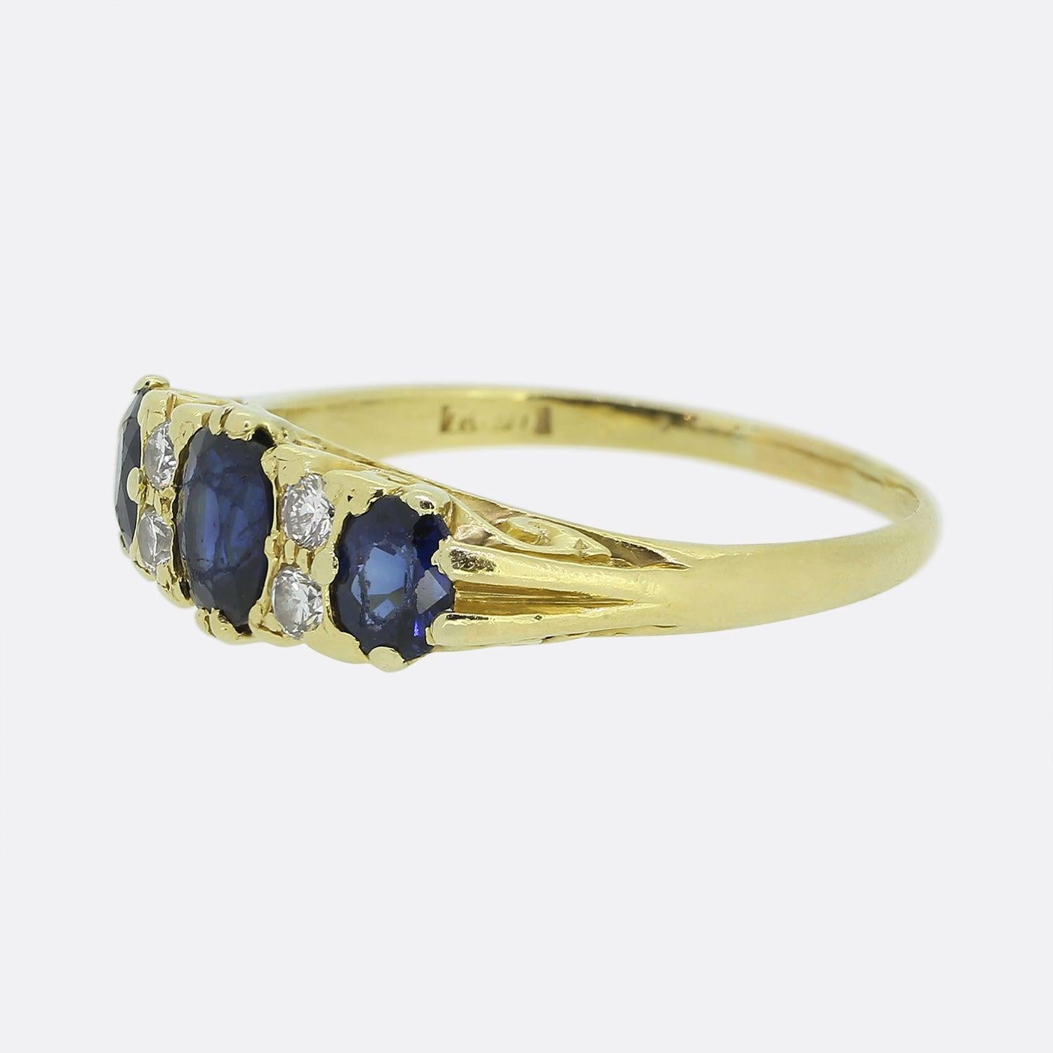 Here we have a classical three-stone sapphire and diamond ring. This vintage piece showcases three oval faceted sapphires across the face with the centre stone being slightly larger than its two counterparts. Each sapphire possesses a royal navy