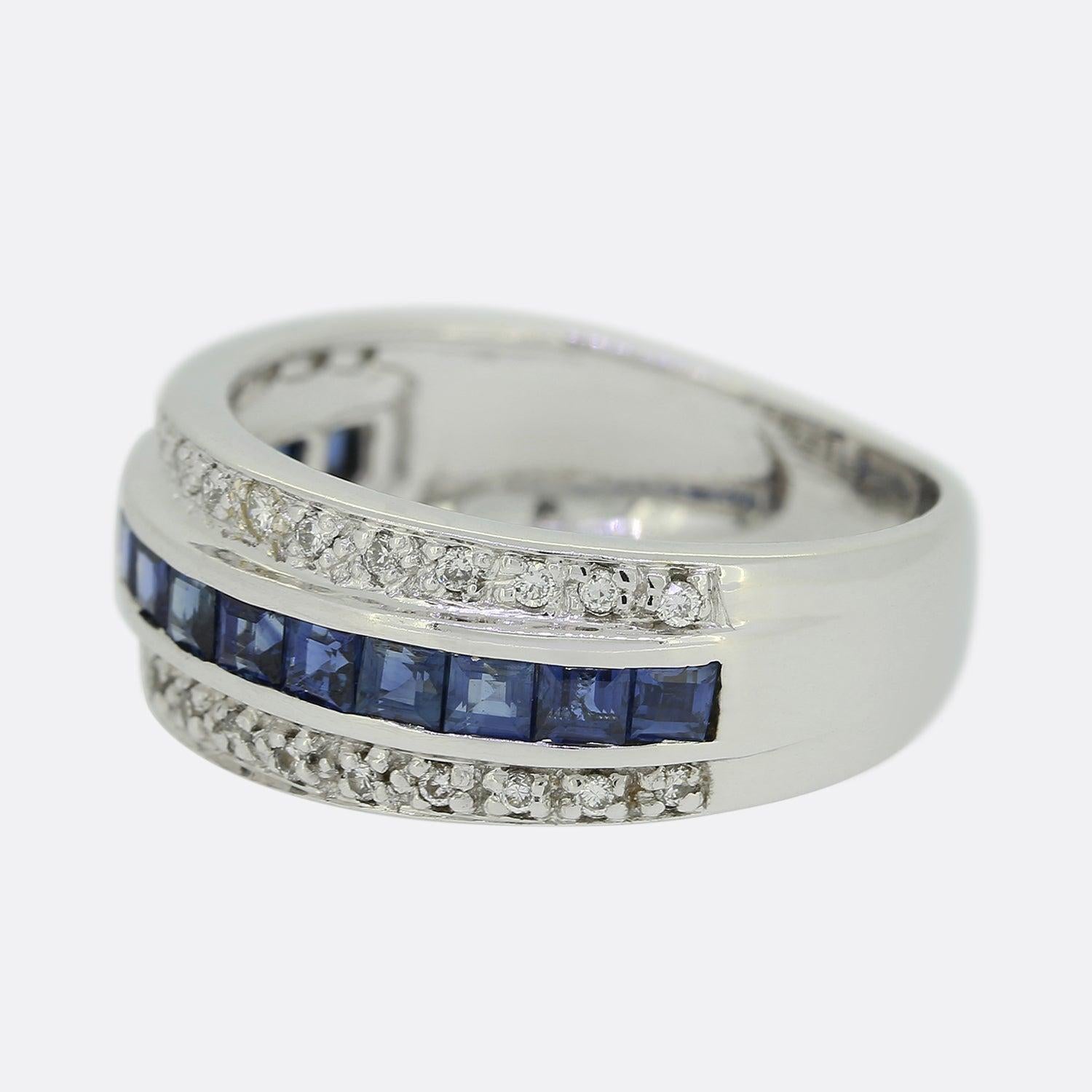Here we have a lovely sapphire and diamond ring. Crafted from 18ct white gold, this vintage piece showcases a mid section of channel set square shaped sapphires which are complimented above and below by a single row of eight cut diamonds.