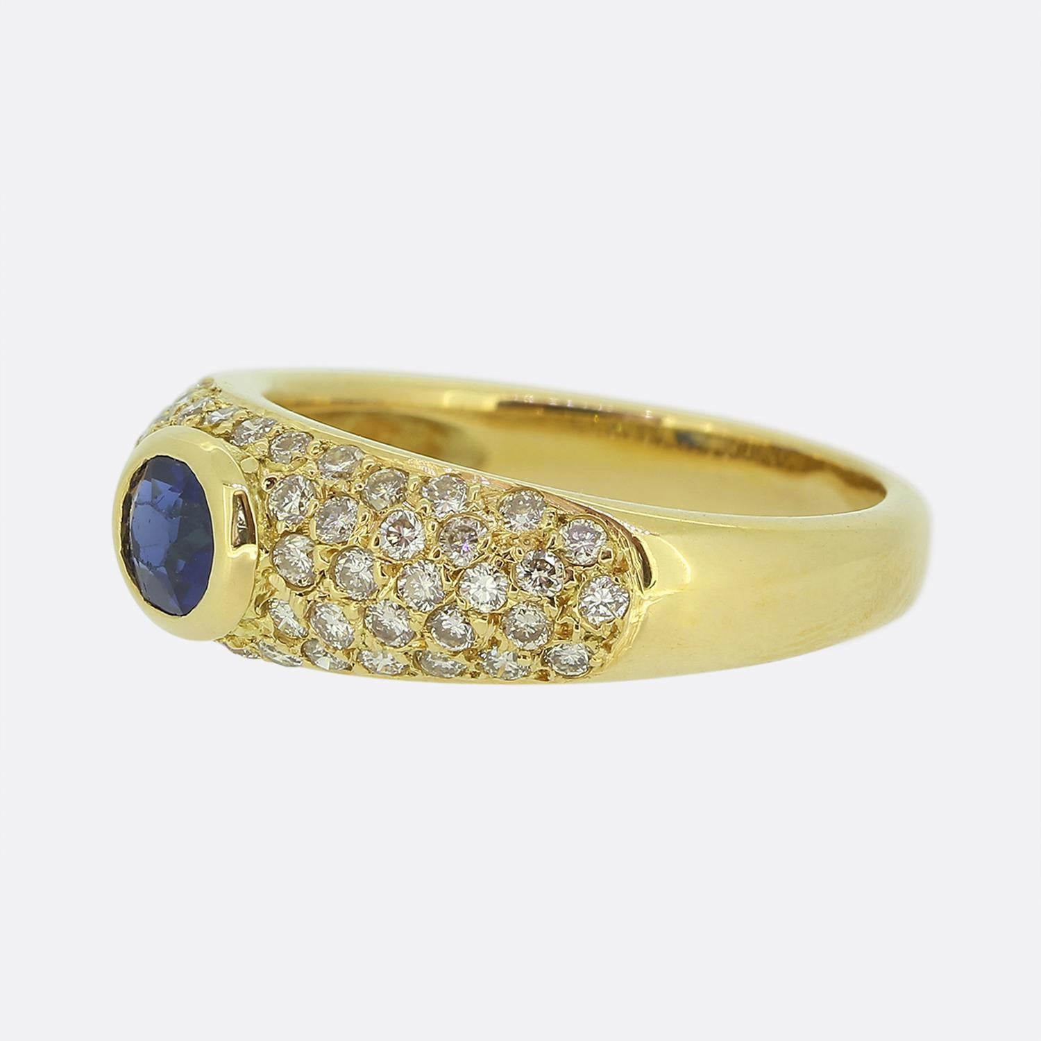 Ecco un elegante e raffinato anello con zaffiro e diamante. Questo pezzo vintage è stato realizzato in oro giallo 18 carati e presenta un singolo zaffiro ovale sfaccettato al centro del quadrante. Questa pietra principale è leggermente rialzata in