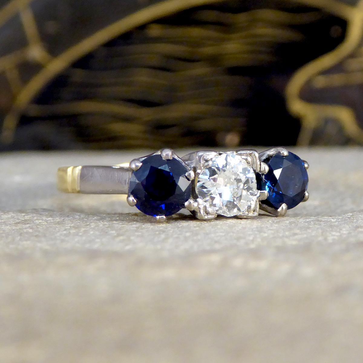 Discover the timeless elegance of our vintage Sapphire and Diamond three stone ring, masterfully crafted with an 18ct yellow gold band and an 18ct white gold setting. At the heart of this exquisite piece lies a radiant diamond, flanked on either
