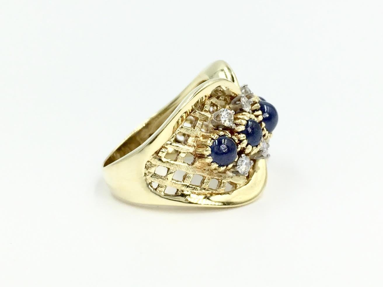 Circa 1965. This uniquely designed 14k yellow gold wide ring features 5 cabochon blue sapphires and 8 round diamonds at approximately .16 carats total weight. Diamonds are approximately G color, SI1 clarity. Beautiful open lattice detail is hand