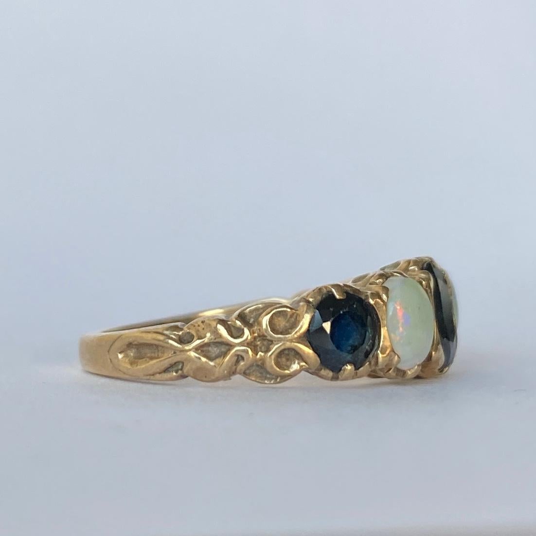 This gorgeous mix of inky blue sapphire and colourful opal is stunning. The sapphires total approx 90pts and in between these stones sit two opals. The ring is modelled in 9ct gold and was made in London, England. 

Ring Size: M 1/2 or 6 1/2 
Band