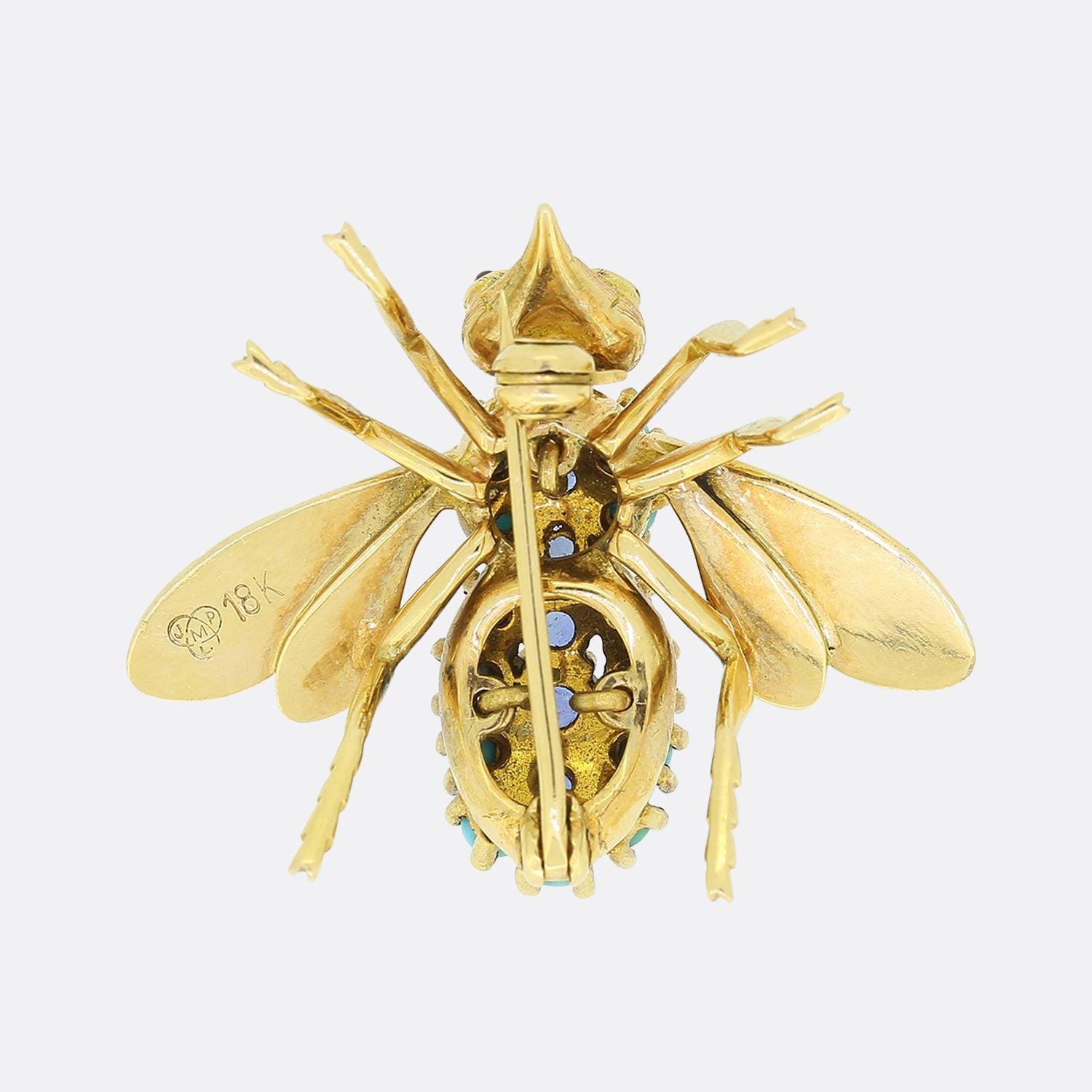This is a vintage 18ct yellow gold brooch crafted into the shape of a fly. This ornate piece possesses expertly engraved features including wings, head and legs whilst the body is set with multiple round, claw set sapphires and turquoises. This