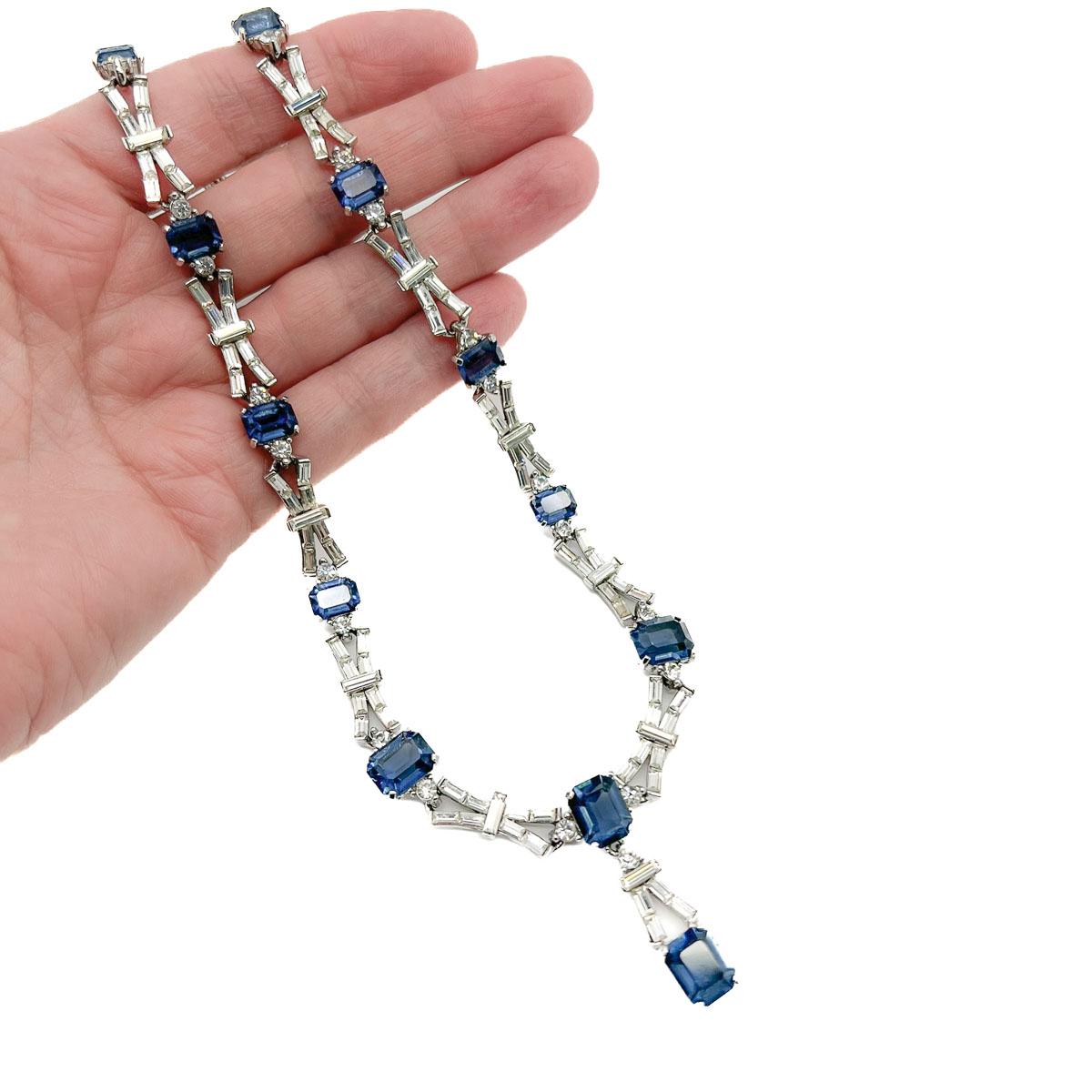 Un collare Art of Vintage in zaffiro. Una deliziosa e pudica collana con ciondolo ispirata al design Art Deco. Caratterizzato da grandi pietre di cristallo blu zaffiro con taglio smeraldo. Le maglie sono incastonate alla perfezione con cristalli