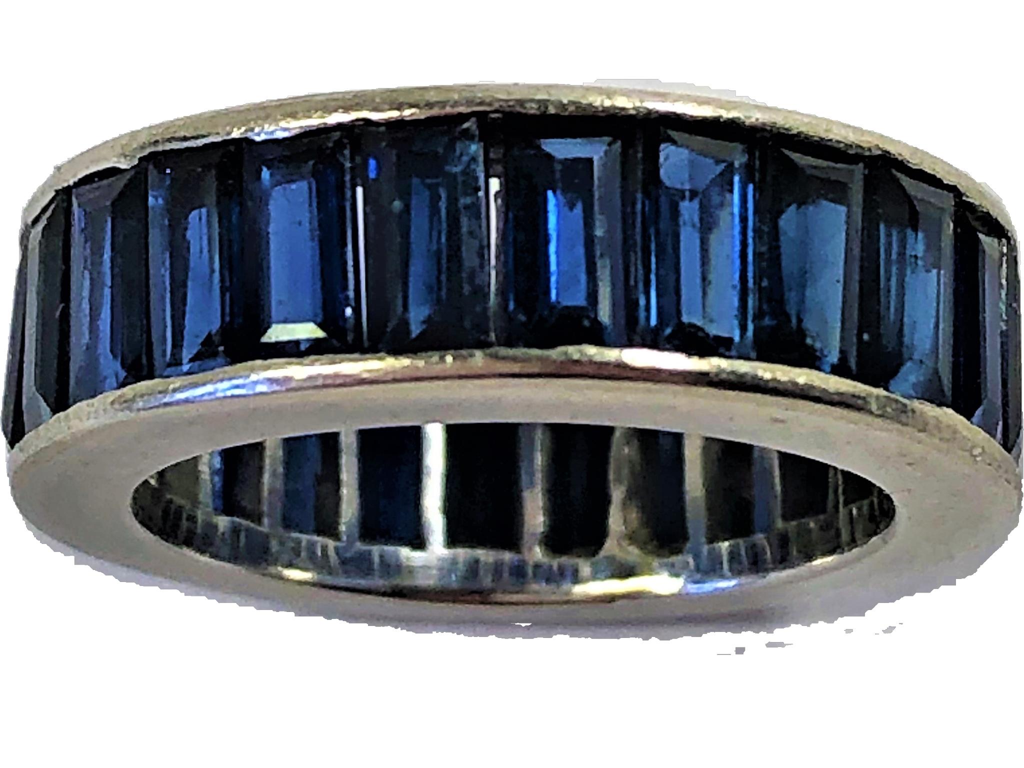 This vintage platinum eternity band is set with deep blue, baguette cut natural sapphires weighing an approximate total of 5CT.  Measures 6mm wide (just short of 1/4 inch). Ring size 4 3/4.  Gross weight 7.1grams. Shown with a vintage platinum