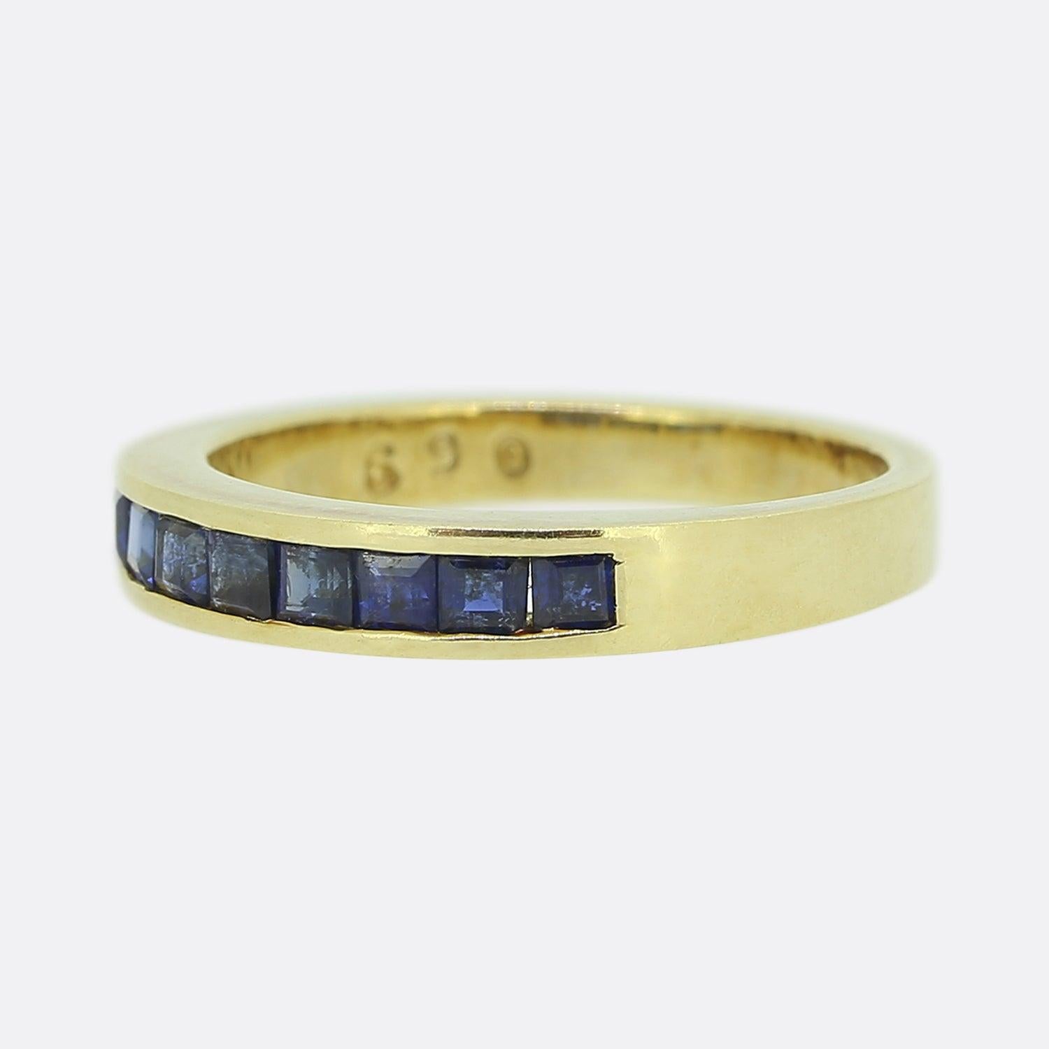 Here we have a classic sapphire band ring. A 14ct yellow gold mount plays host to nine square calibrated sapphires; all of which have been neatly rub-over set in a single line formation and are perfectly matched in terms of their rich dark navy
