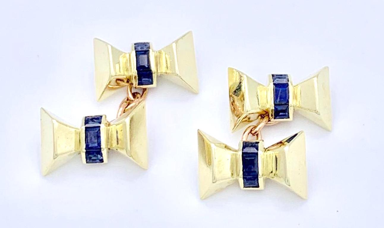 Charming pair of 14K gold cufflinks in the shape of bows. Each bow is set with three sapphires in calibré cut. The chains that link the bow are made out of red gold.