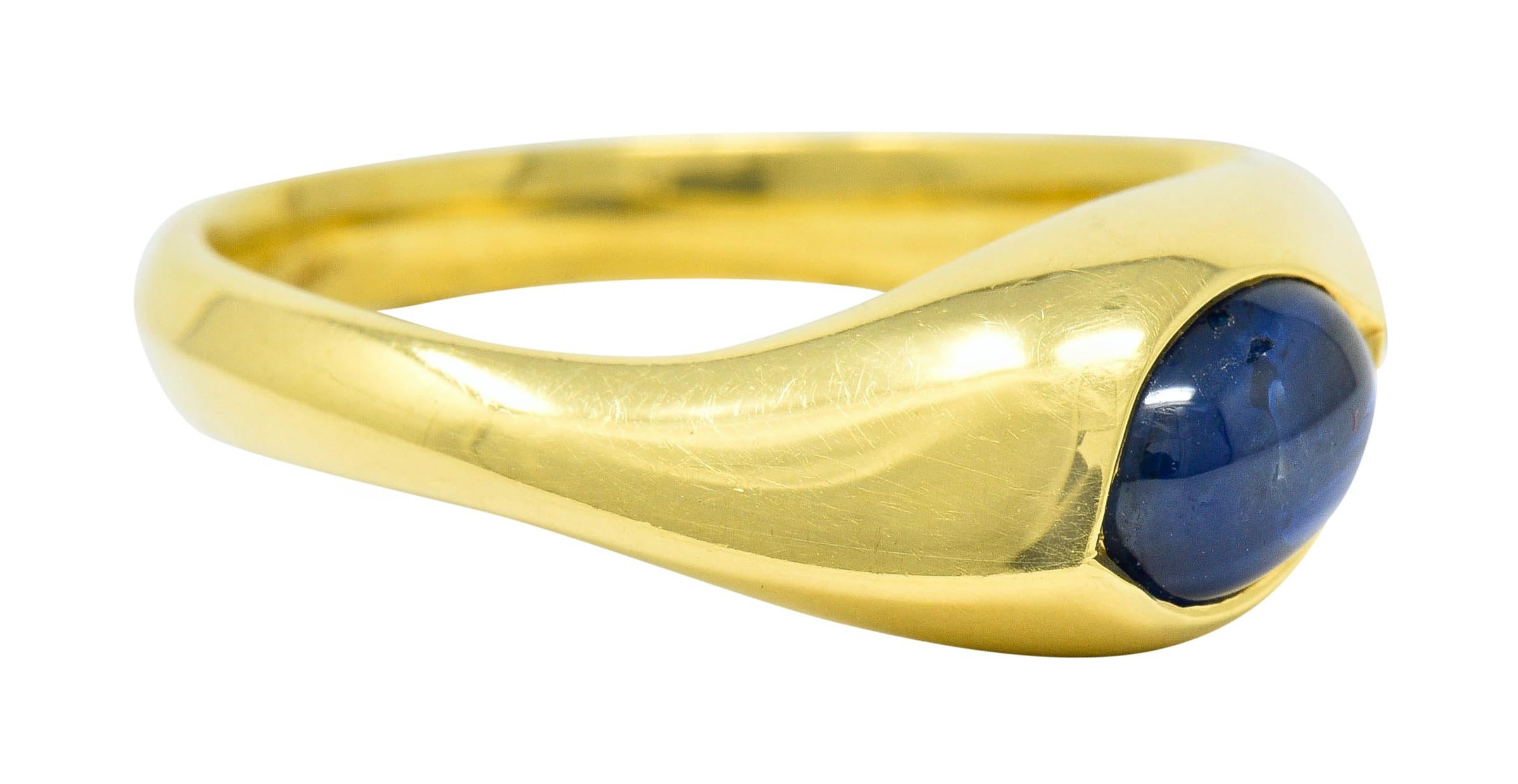 Band ring with a slight torqued design and knife edged shank

Centers a flush set oval sapphire cabochon weighing approximately 0.80 carat

Bright royal blue in color and translucent with natural inclusions

Inscribed with maker's mark and 18K for
