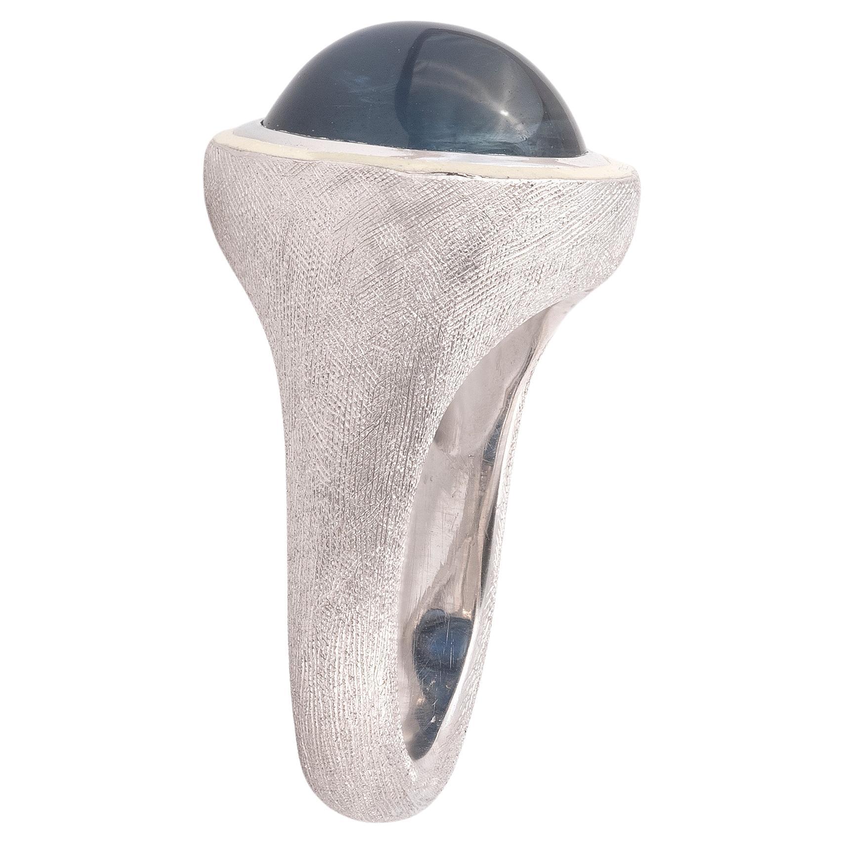 In brushed white gold with central cabochon sapphire weighing approx. 9ct framed by cream enamel
Circa 1970
Size 7 1/4
Weight: 15,44gr.