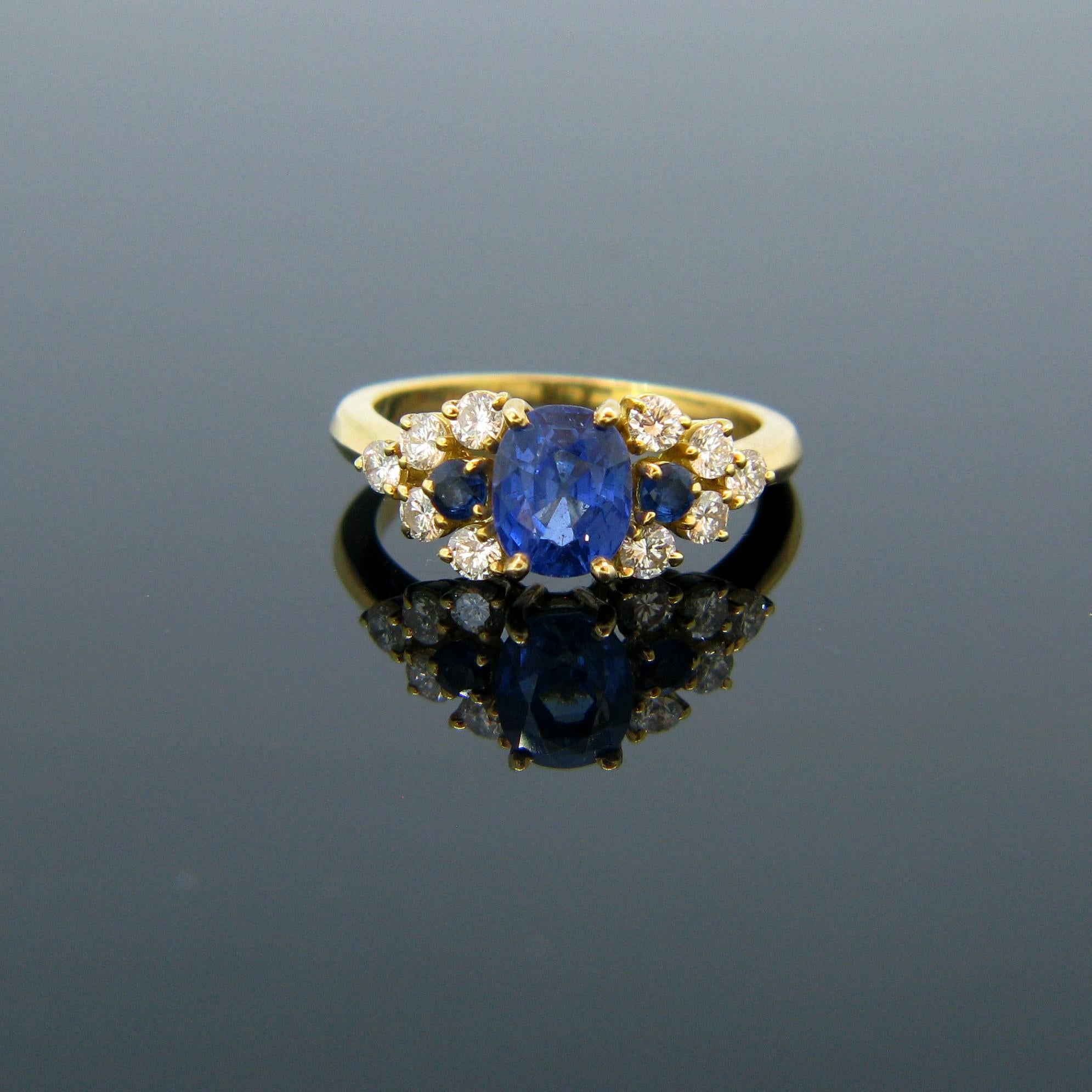 This beautiful ring is set with an oval cut natural sapphire weighing approximately 1.65ct. The sapphire is a Ceylon with no indications of heating. It is also set with two sapphires and 10 round brilliant cut diamonds. It is fully made in 18kt