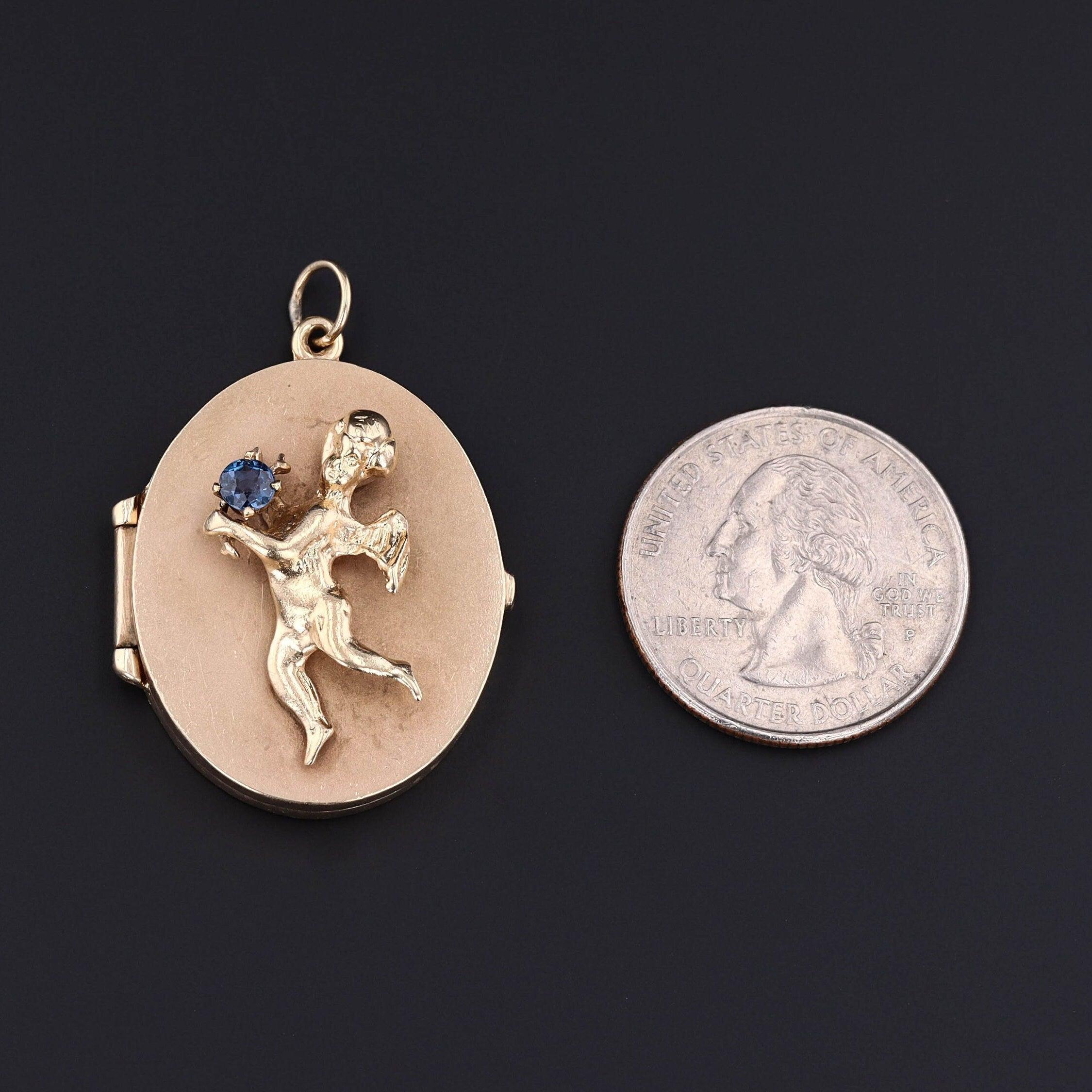 This vintage locket (circa 1950-1970) features a cherub of 14k gold holding a vibrant blue sapphire.

The piece measures 1.6 inches form the top of the jump ring to bottom by 1.1 inch wide (when closed) and is in good condition with light surface
