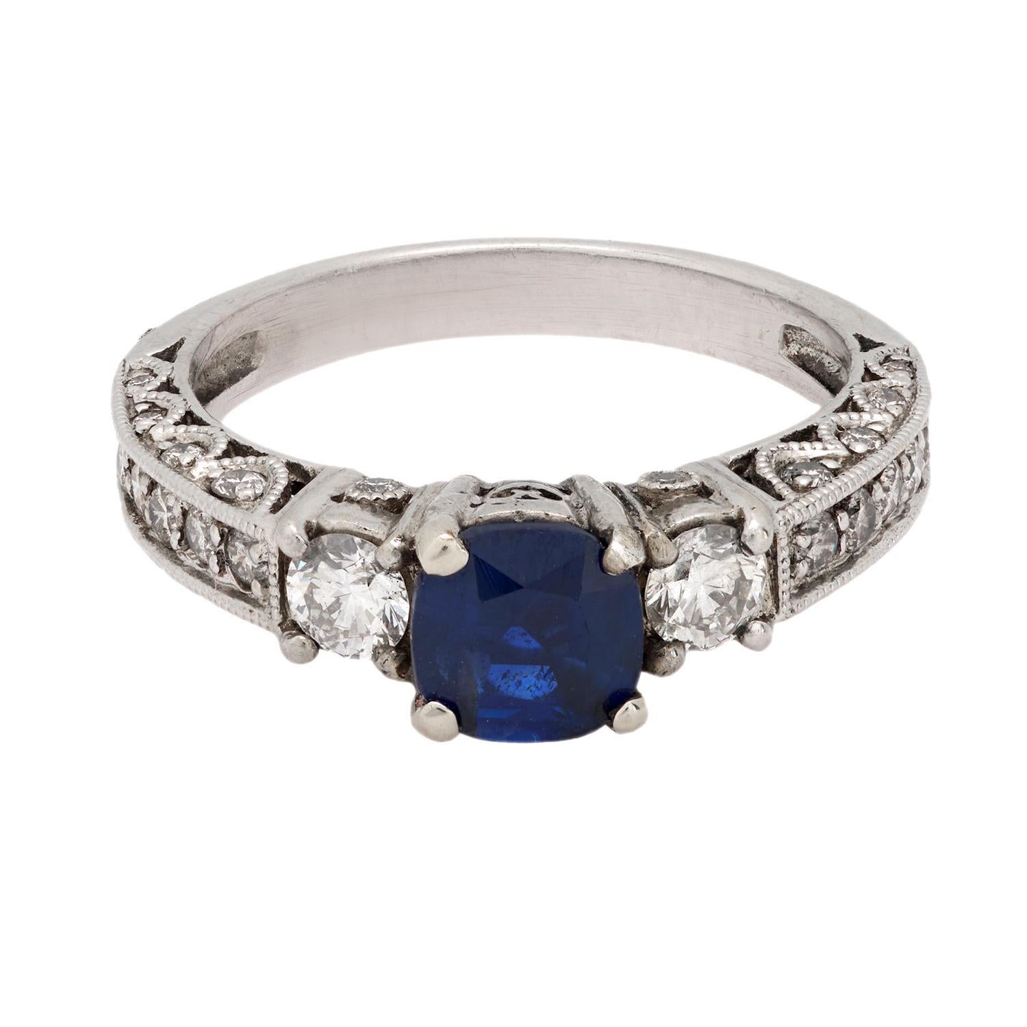 This vintage ring from the 1990s is crafted in 14k white gold and features a cushion cut sapphire weighing approximately 0.90 carats. Surrounding the center stone are 34 round brilliant cut diamonds totaling approximately 0.50 carats, graded H-I