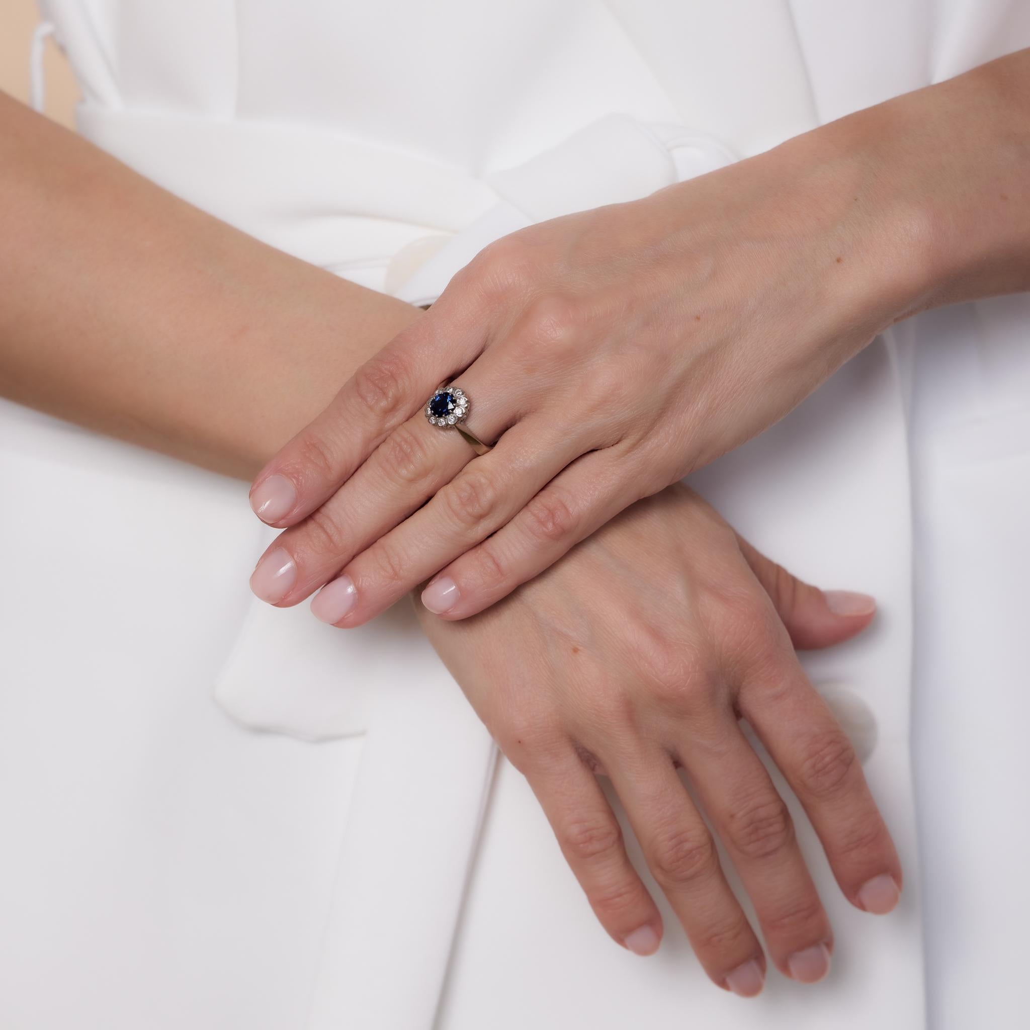 Dieser Vintage-Ring aus 18 Karat Weißgold besteht aus einem blauen Saphir mit 0,93 Karat Ovalschliff, umgeben von 10 runden Diamanten mit Brillantschliff von insgesamt 0,22 Karat, Farbe F, Reinheit VS. Ein zeitloses und elegantes Design aus den