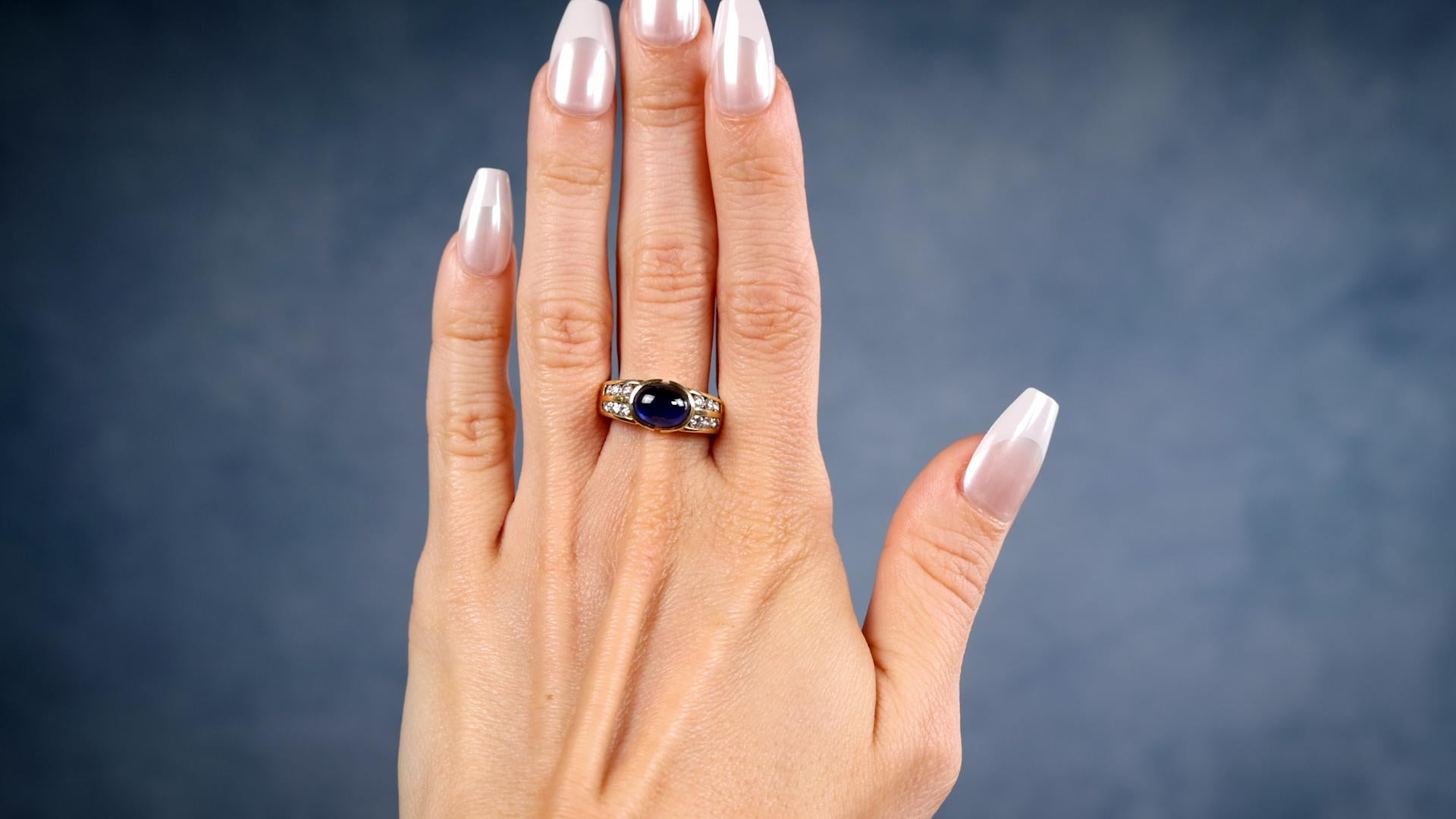 Ein Vintage Saphir Diamant 18k Gelbgold Ring. Mit einem ovalen Saphir im Cabochon-Schliff mit einem Gewicht von etwa 3,00 Karat. Akzentuiert durch 12 runde Diamanten im Brillantschliff mit einem Gesamtgewicht von ca. 0,60 Karat, eingestuft als