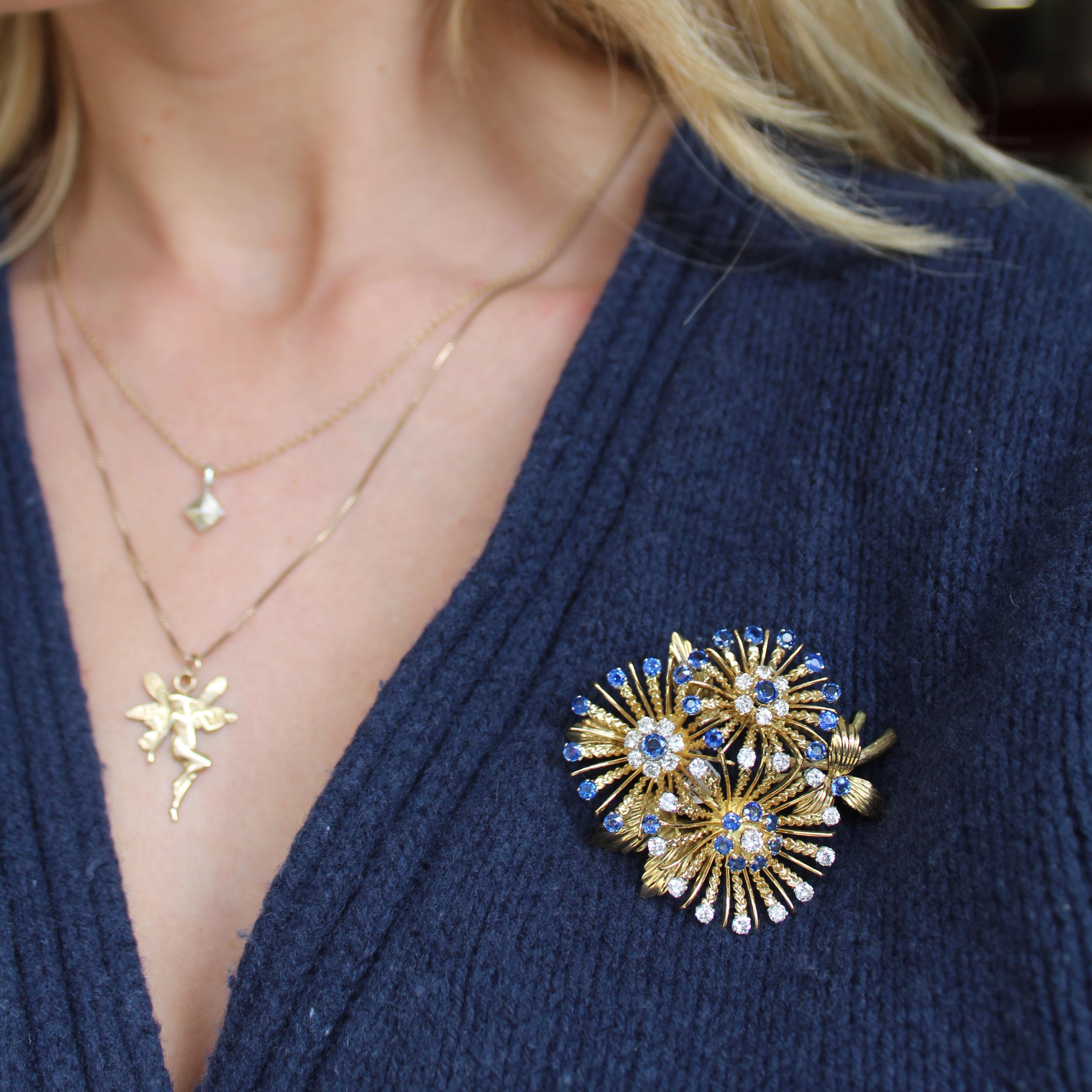 A vintage sapphire, diamond and gold brooch, designed as three abstract flowers, with cluster centres, two set with round faceted sapphire centres and round brilliant-cut diamond surrounds, with sapphires set at the petal edges, the third set with a