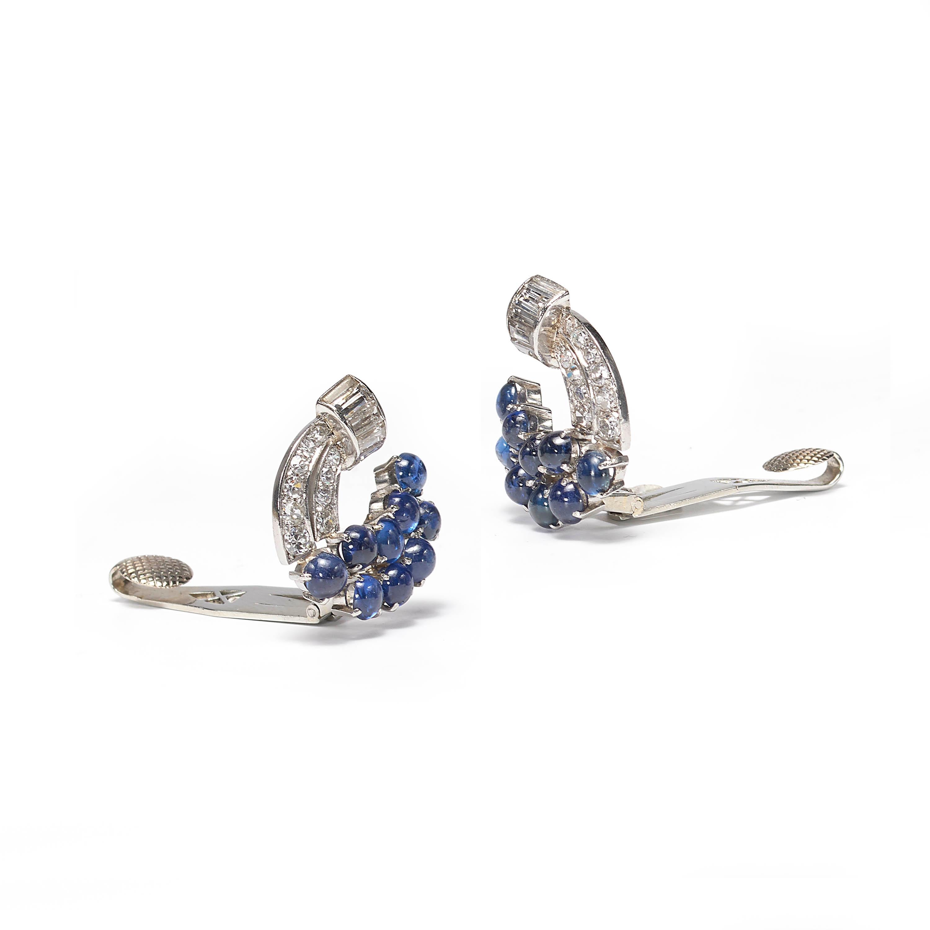 A pair of vintage sapphire and diamond ear clips, comprised of cabochon-cut sapphires weighing an estimated total of 5.00ct, and single-cut and baguette-cut diamonds, weighing an estimated total of 1.80ct, in a scroll design, mounted in platinum.