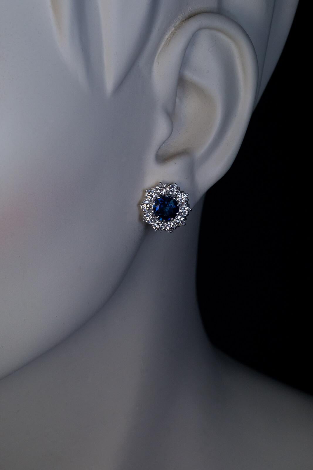 The earrings are crafted in white 14K gold. They are centered with round dark blue sapphires (approximately 1.67 cts and 1.65 cts) surrounded by high quality brilliant cut diamonds (bright white and clean, E-F color, VVS2-VS1 clarity).  Estimated