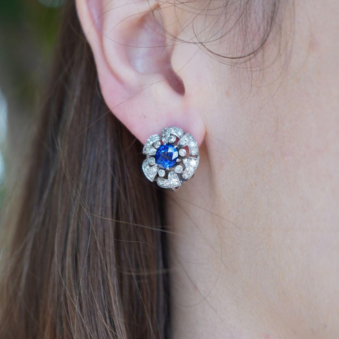 These vintage French earrings are crafted in platinum with a 18k white gold backing, bearing the French eagle head hallmark. Each earring features a vibrant round brilliant-cut sapphire at the center, weighing approximately 1.25–1.50 carats each,