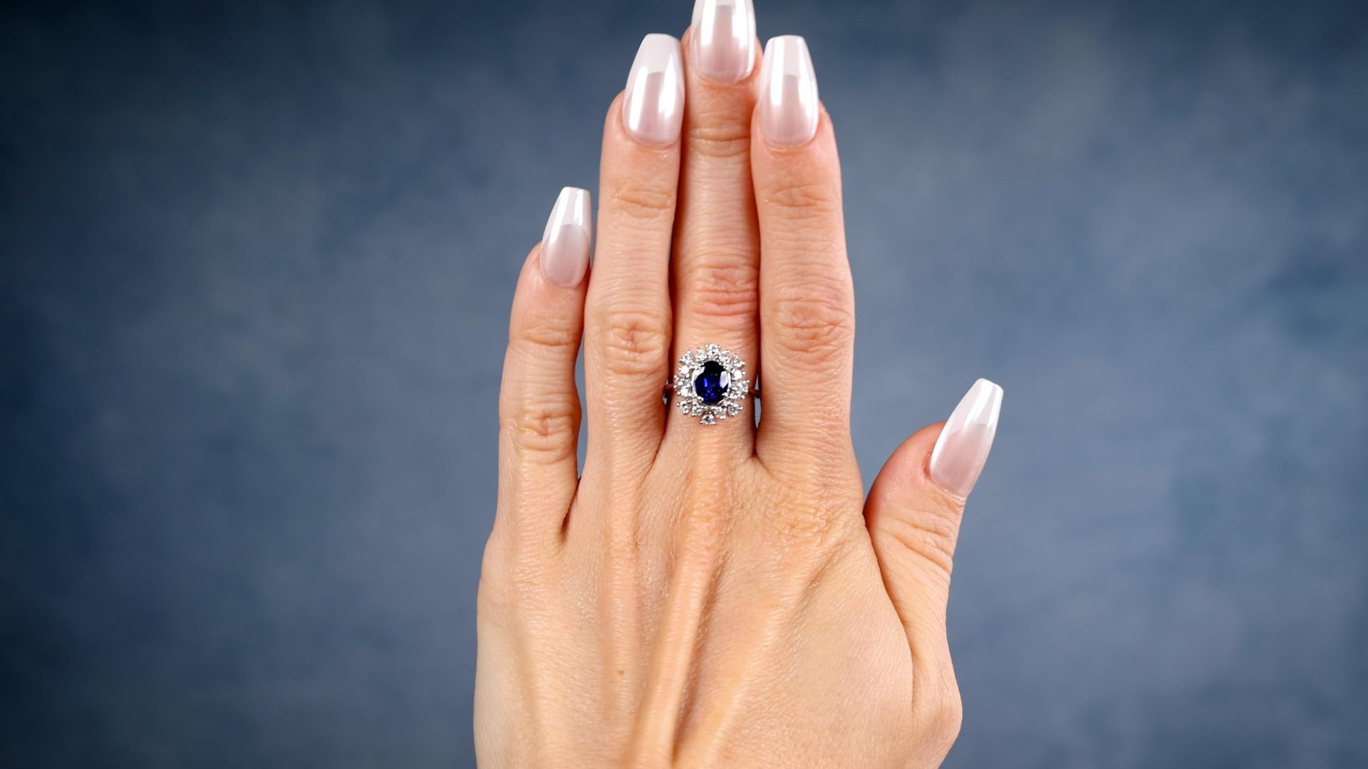 One Vintage Sapphire Diamond Platinum Cluster Ring. Featuring one oval mixed cut sapphire weighing approximately 1.40 carats. Accented by 16 round brilliant cut diamonds with a total weight of approximately 0.80 carat, graded near-colorless, VS-SI