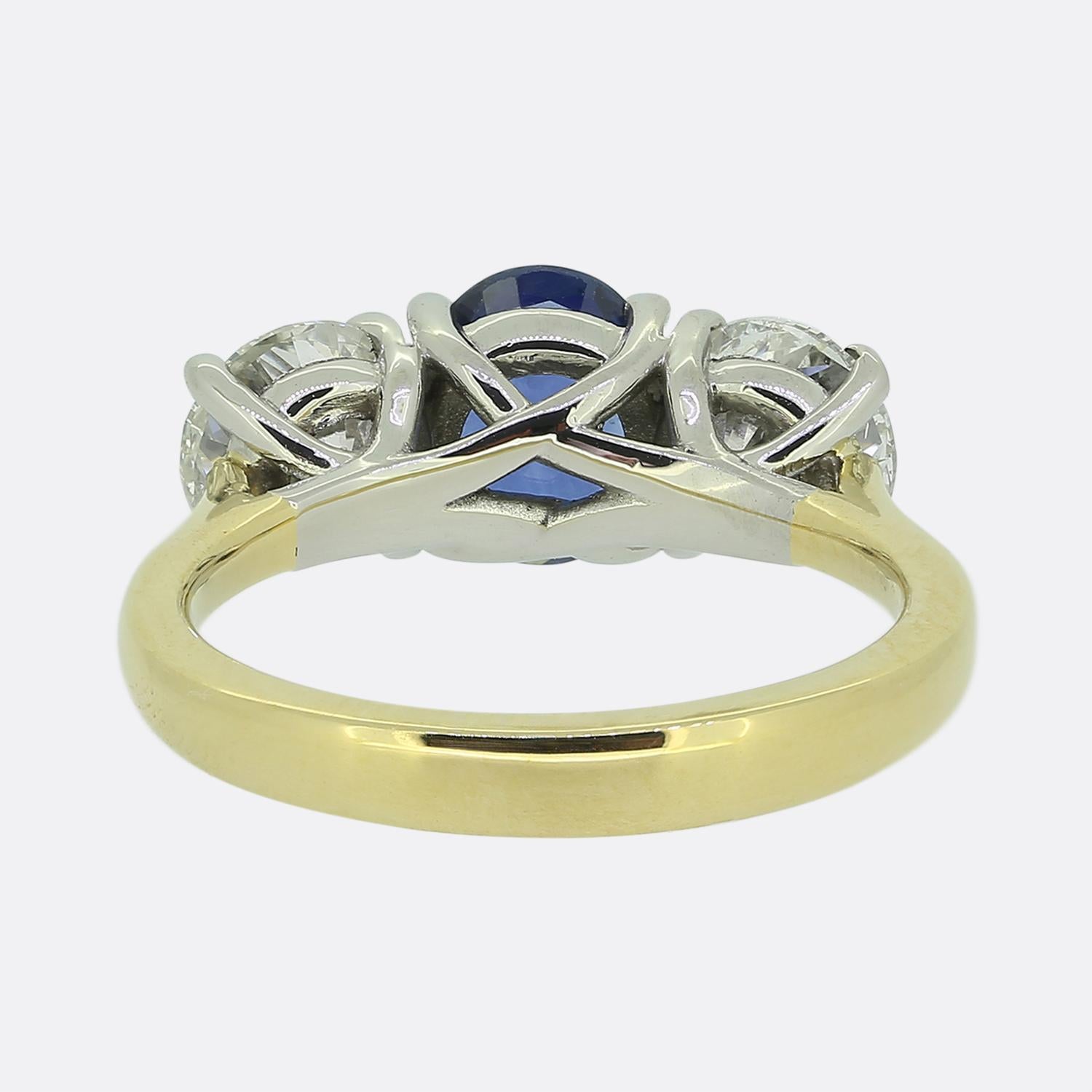 Il s'agit d'une bague vintage à trois pierres en saphir et diamant, réalisée en or jaune 18ct. La bague présente un saphir bleu ovale central flanqué de deux diamants ronds de taille brillant. Le bleu moyen à foncé du saphir est très bien mis en