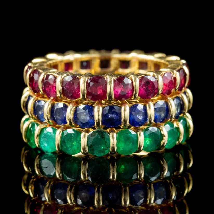 A magnificent vintage eternity ring set made by “Hennell” in the 20th Century. It consists of a trilogy of eternity rings modelled in 18ct gold and tension set with a full band of rubies, sapphires and emeralds (approx. 2ct of each gemstone). 