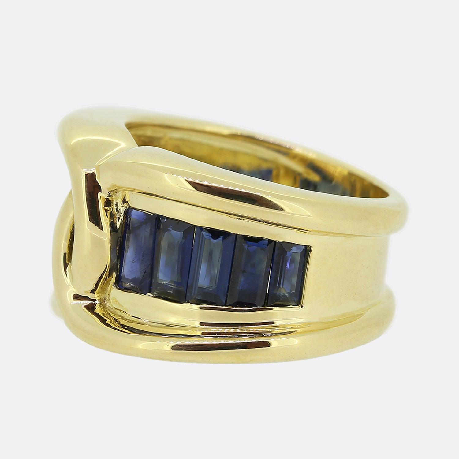 Here we have a large vintage sapphire knot ring. This wide piece has been crafted from 18ct yellow gold with the face showcasing an interwoven motif. This centralised design is flanked on either side by a graduating row of rub-over set royal blue