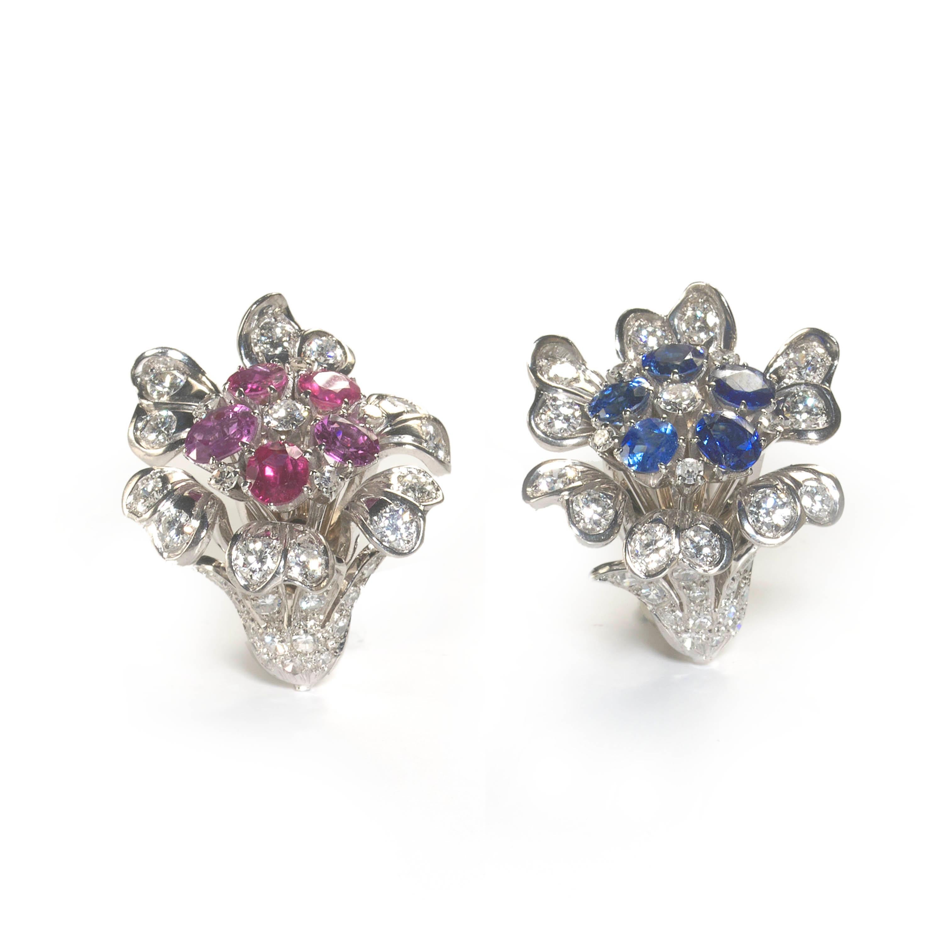 A pair of vintage ruby, sapphire and diamond set cornucopia flower cluster earrings, with stylised cornucopia shaped flower heads, with round brilliant-cut diamonds set in the petals and eight-cut diamonds set in the calyx. The centre of one earring