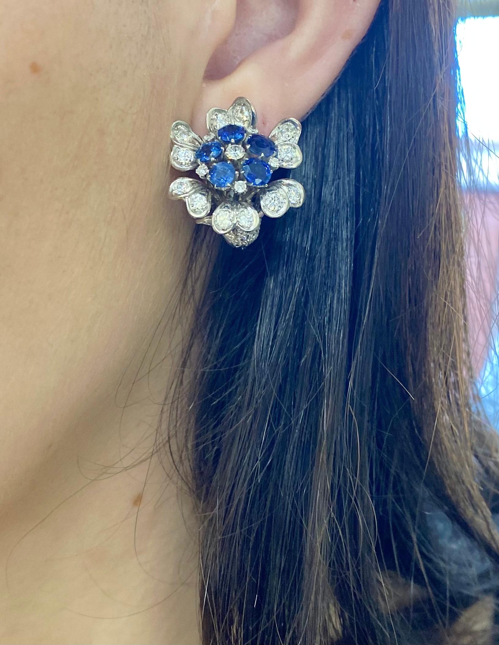 A pair of vintage ruby, sapphire and diamond set cornucopia flower cluster earrings, with stylised cornucopia shaped flower heads, with round brilliant-cut diamonds set in the petals and eight-cut diamonds set in the calyx. The centre of one earring