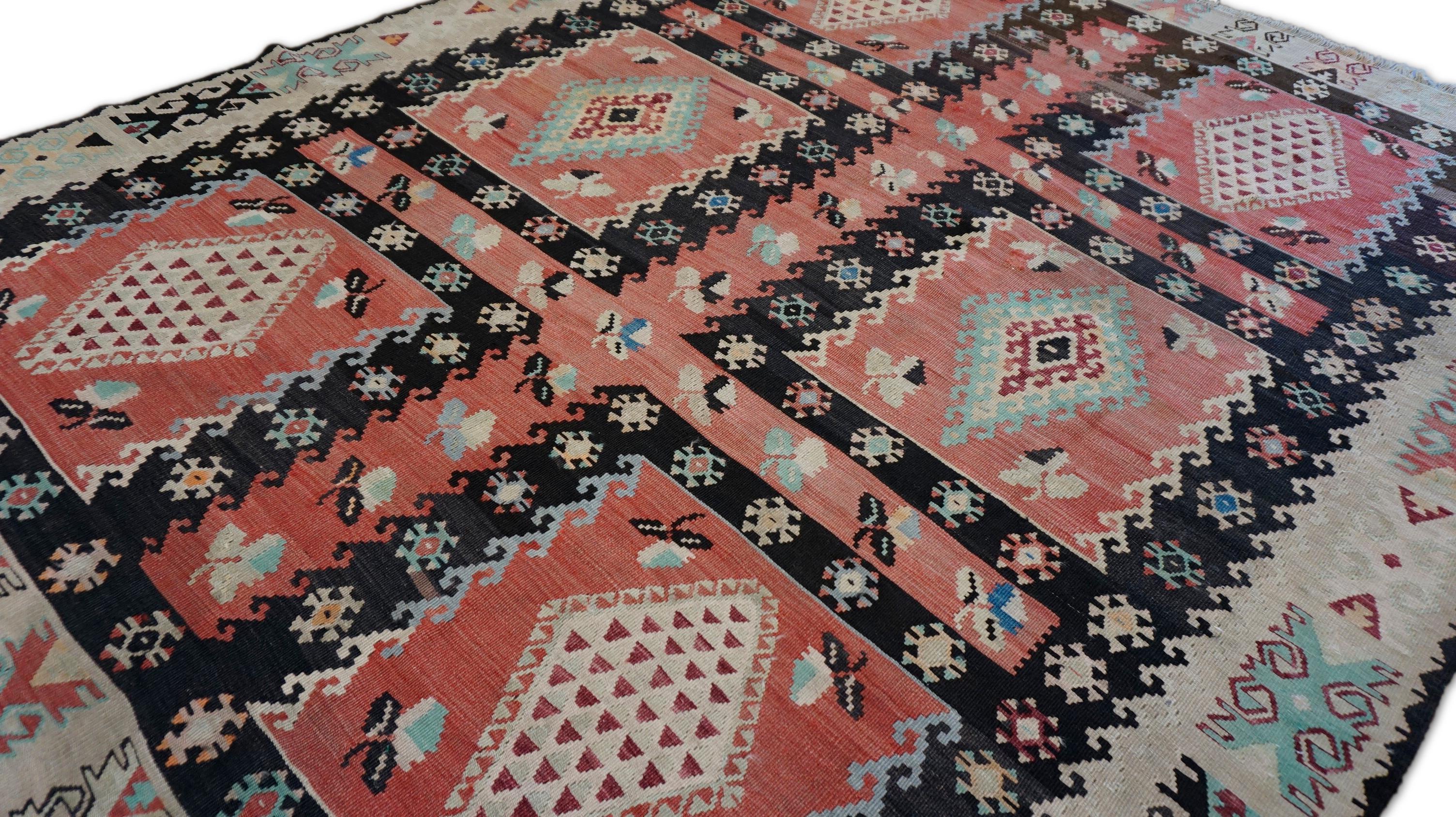 Este llamativo kilim vintage de lana tejida a mano presenta un atrevido diseño tribal definido por tonos ricamente saturados y motivos tradicionales. Tejida en una cuadrícula equilibrada de medallones romboidales, la alfombra muestra un vibrante