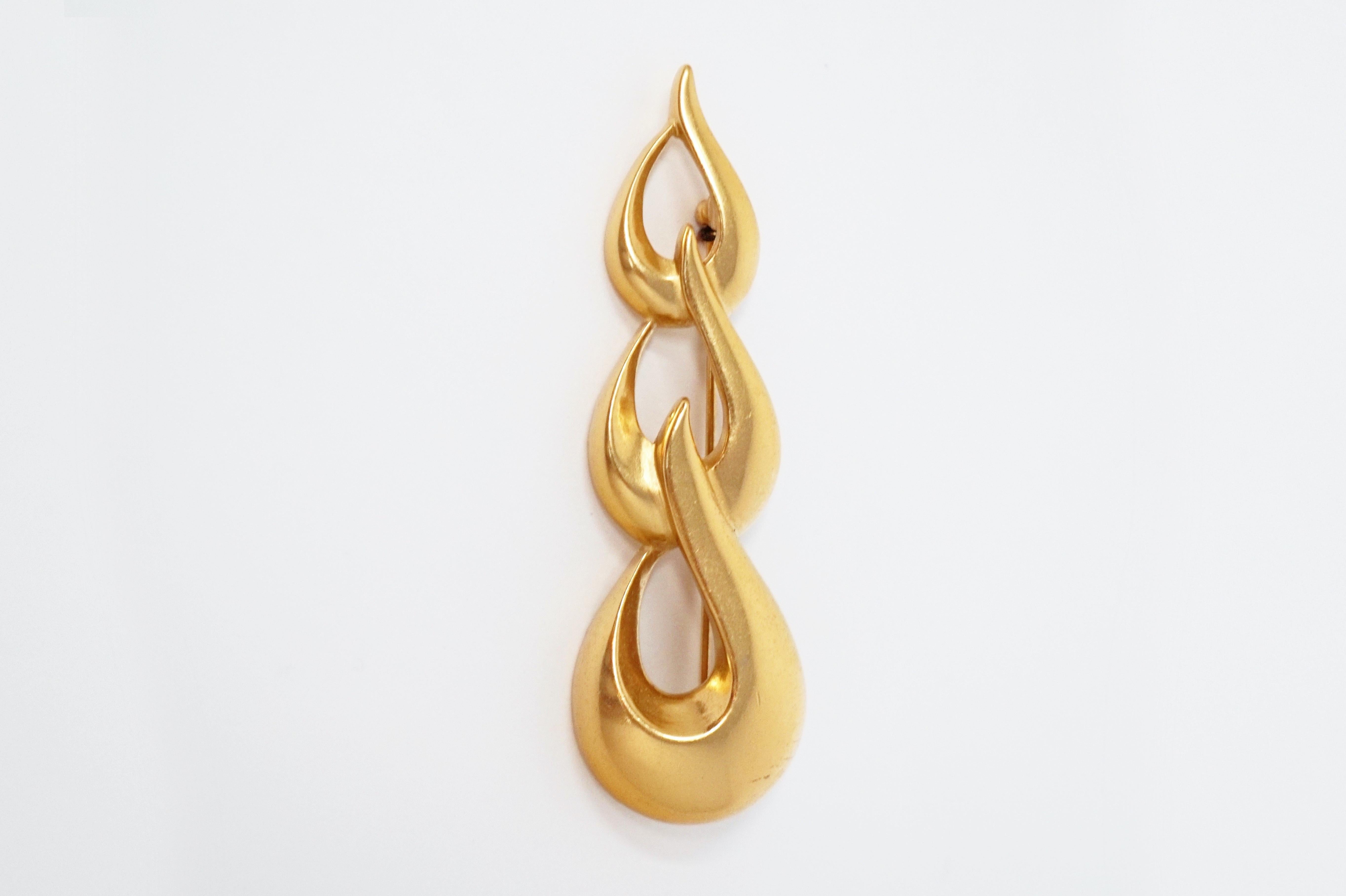 This gorgeous gilt brooch by Monet, circa 1970s, is a wonderful example of the quality and innovative designs that the coveted vintage costume jewelry brand is known for.  With a satin gold-plated finish, this abstract brooch can be styled with