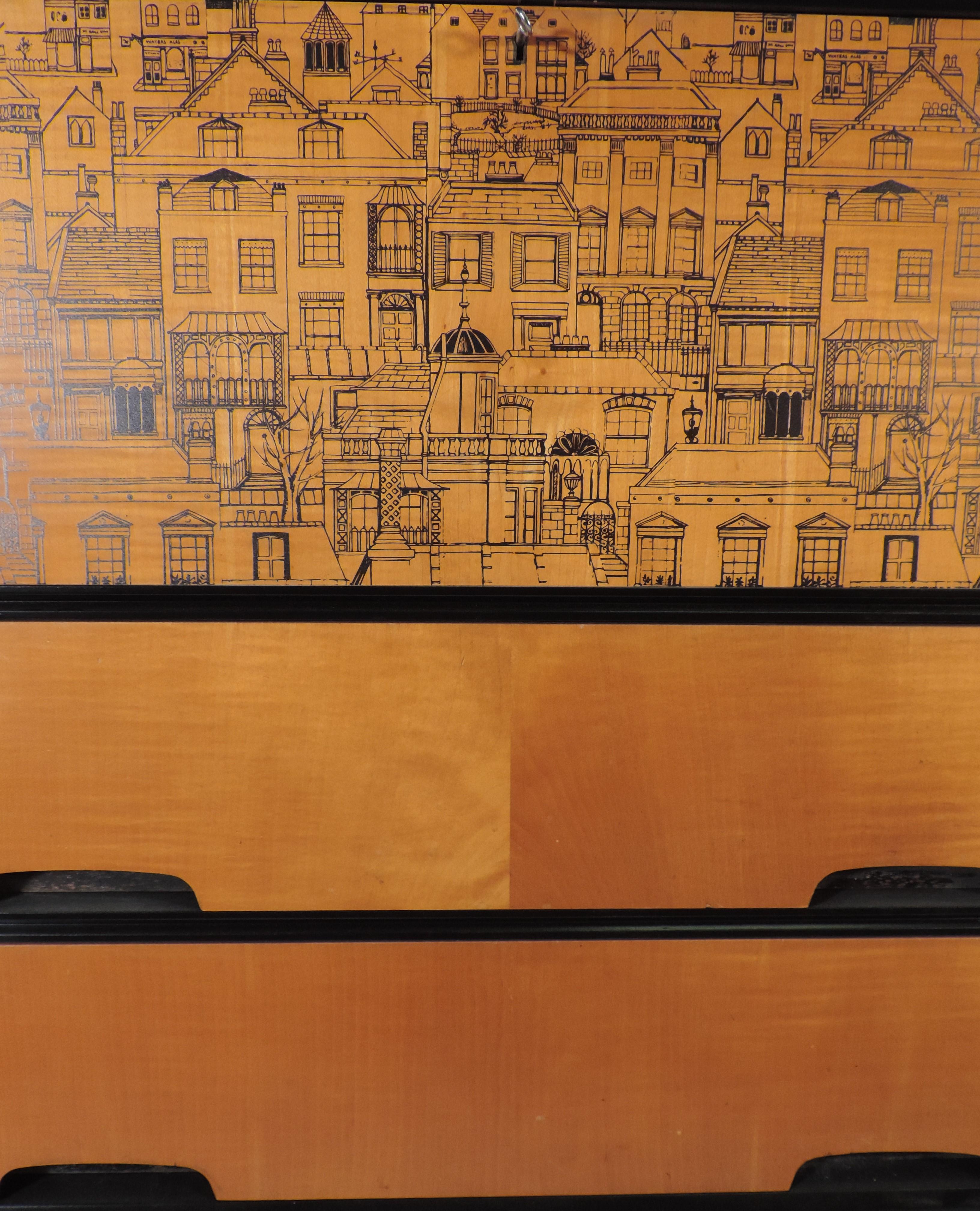 This stylish midcentury satinwood bureau was restyled in our studio to feature a whimsical line drawing of the Regency London Cityscape. The bureau stands on splayed atomic legs with a streamline slanted front and features great recessed handles.