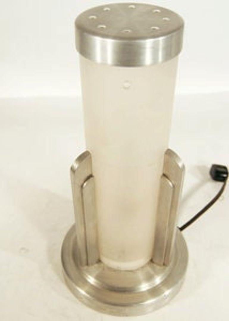 This is a Saturn Lighting company re-edition stepped Art Deco aluminum table lamp that features a frosted cylinder shade in the center.

Made in the USA by Saturn Lighting

Eras: 1930s
Styles: Art Deco
Measurements: 27.9 x x 15.2 CM (H x W x D)