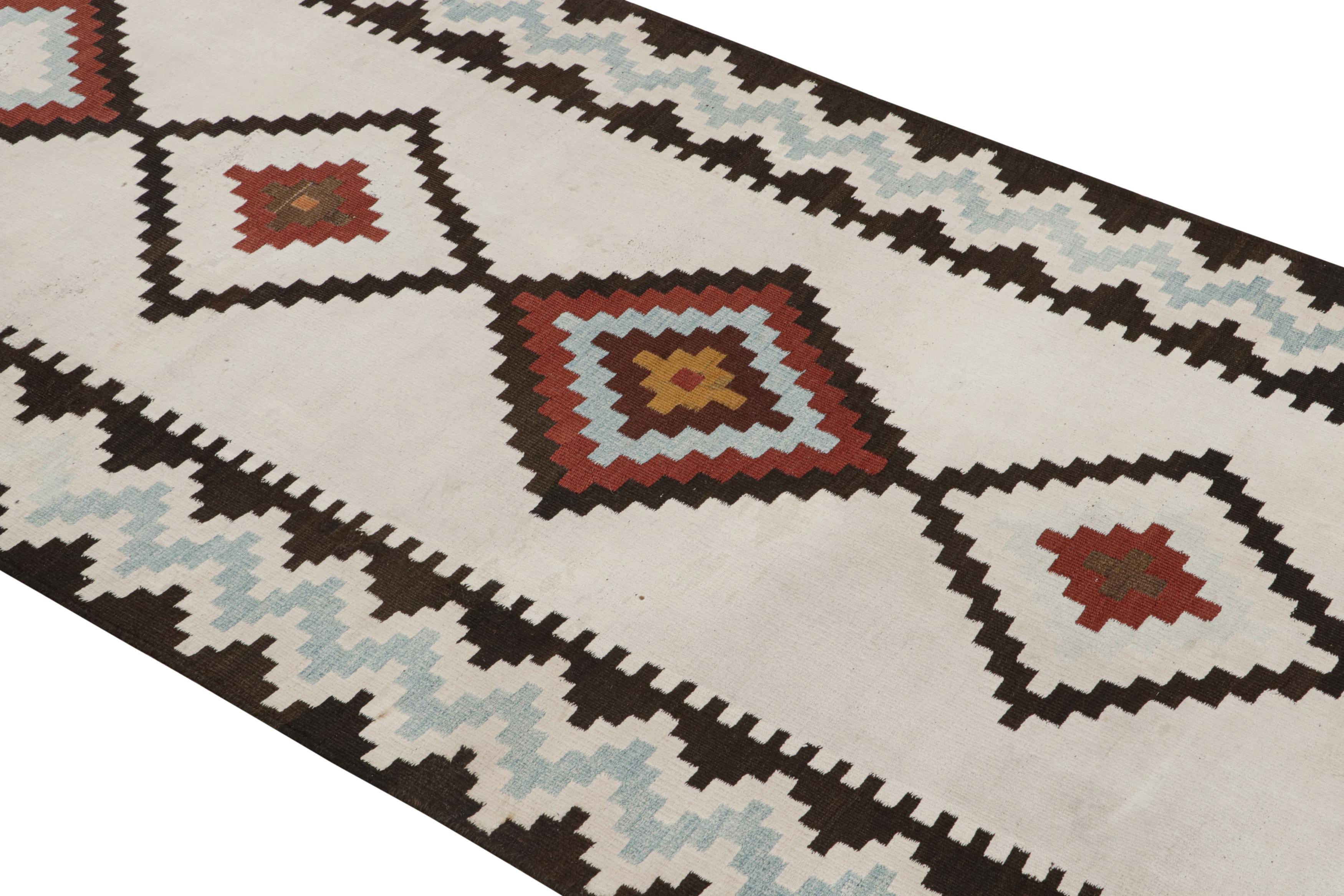 Handwoven in wool originating between 1950-1960, this vintage midcentury Persian Kilim runner hails from the Saveh region of West Persia, acclaimed for a particularly fine wool with a notable sheen distinguishing the most venerated items of the