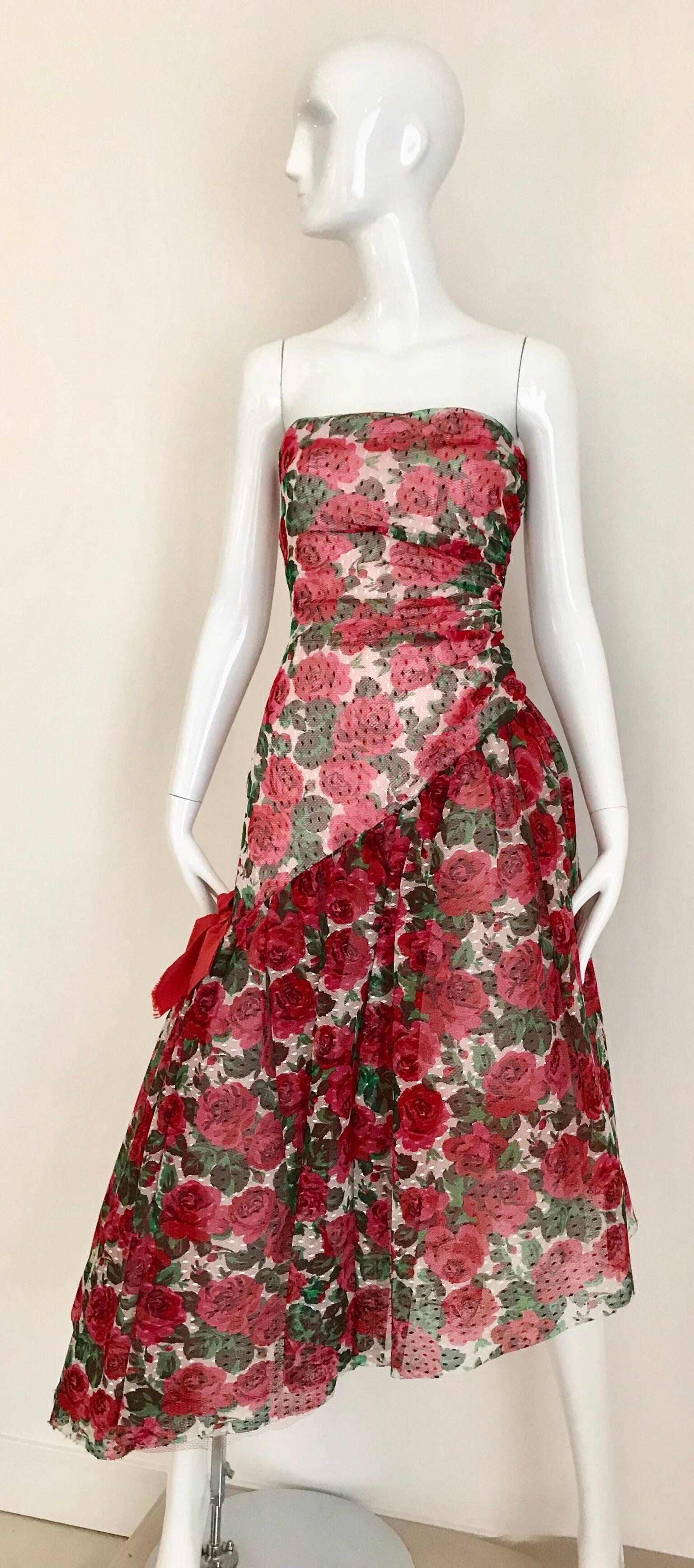 What a fun strapless red roses print tulle party cocktail dress from Arnold Scaasi!  
Dress has asymetrical hem with zipper on the side. Puffy tulle skirt attached underneath.
Extremely flattering fit.  Fit best for size Small
Bust: 32 inch / Waist: