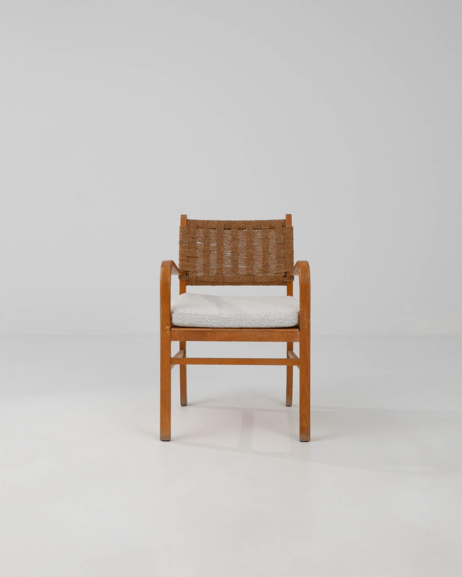 This wooden armchair was made in Scandinavia in the 20th Century. Featuring the natural colors and textures for which Scandinavian design is known; a corded wickerer seat back pairs with russet toned hardwood and a soft boucle seat. The spartan