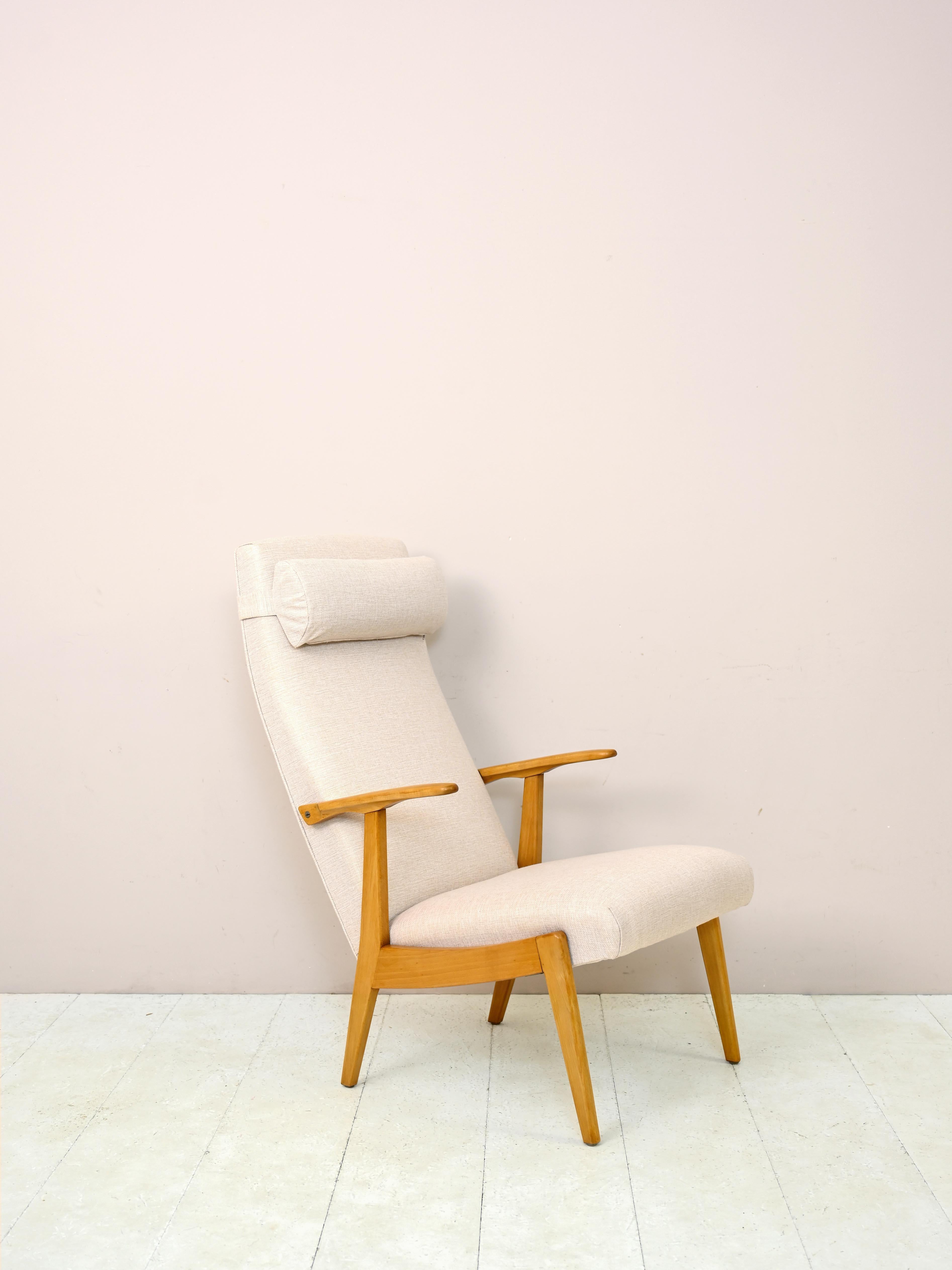 1960s armchair of Swedish manufacture. 

A piece of furniture with modern lines and contemporary appearance consisting of a wooden frame and upholstered seat. 
This armchair is distinguished by its high back and the presence of the headrest